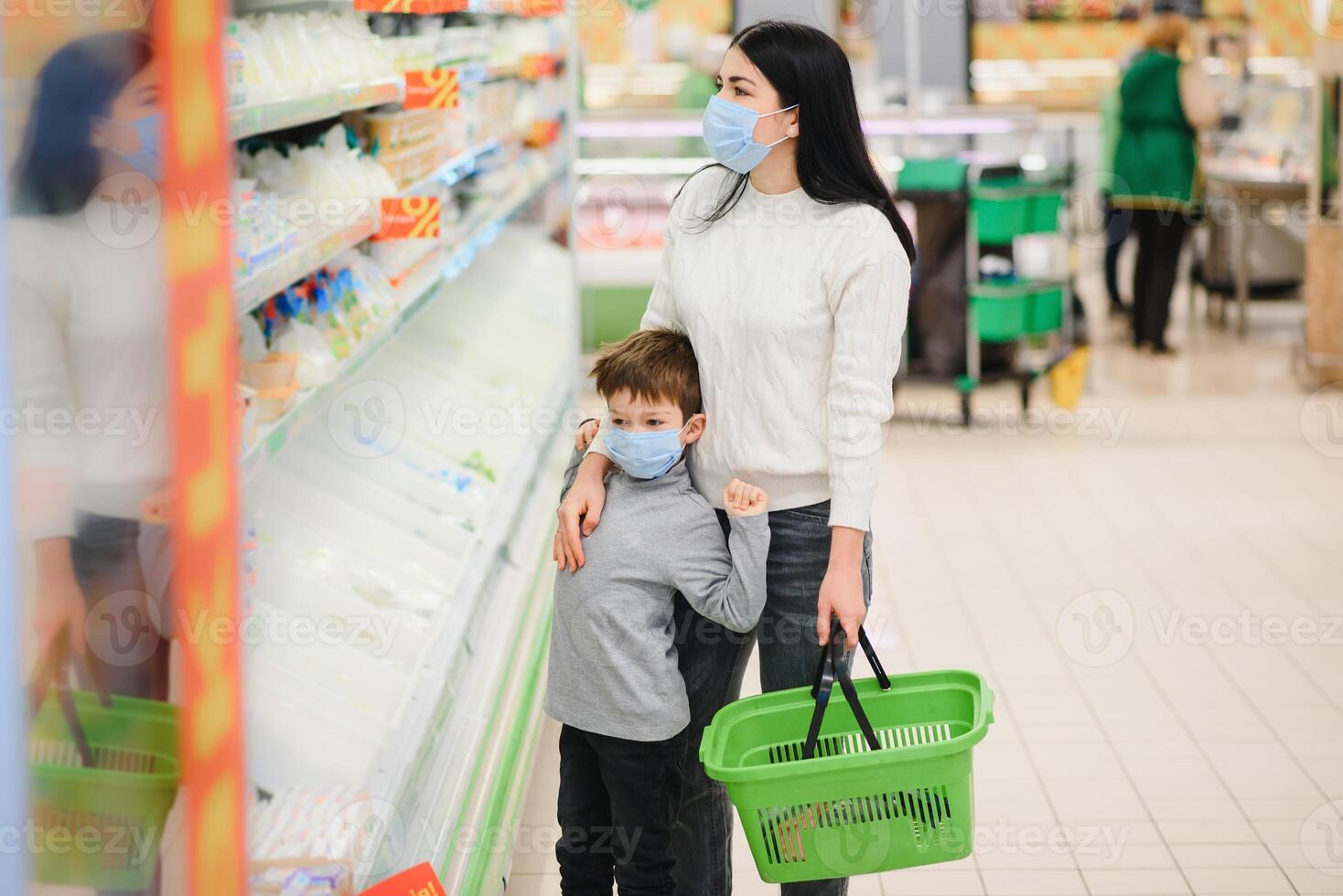 Porträt von ein Mutter und ihr wenig Sohn tragen schützend Gesicht Maske beim ein Supermarkt während das Coronavirus Epidemie oder Grippe Ausbruch. leeren Raum zum Text foto