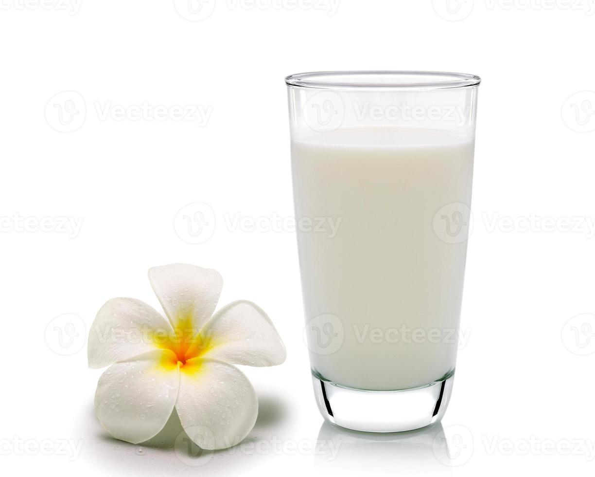Glas Milch und tropische Blumen Frangipani auf weißem Hintergrund foto