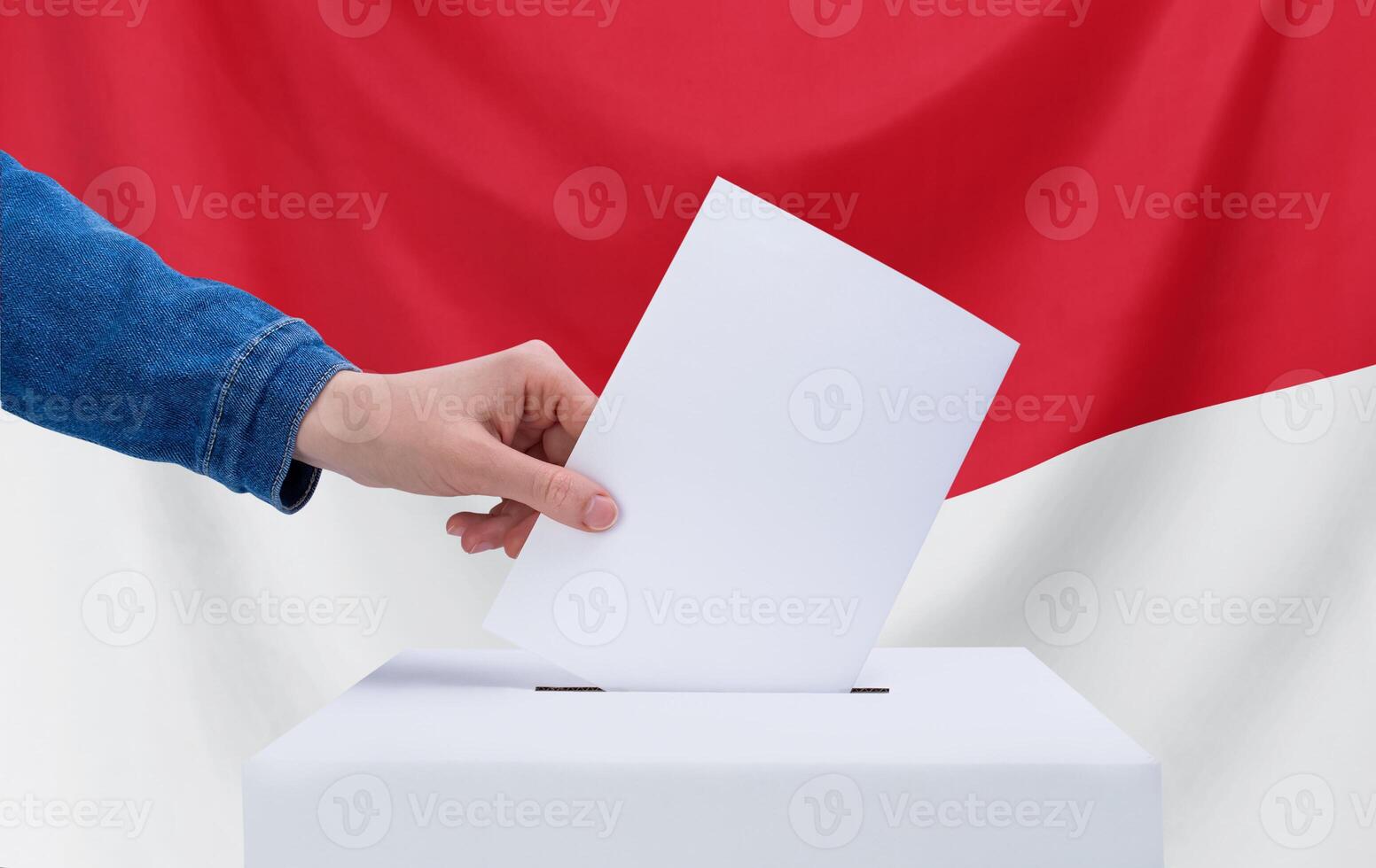 Wahl Konzept. ein Hand wirft ein Abstimmung in das Abstimmung Kasten. Indonesien Flagge auf Hintergrund. foto