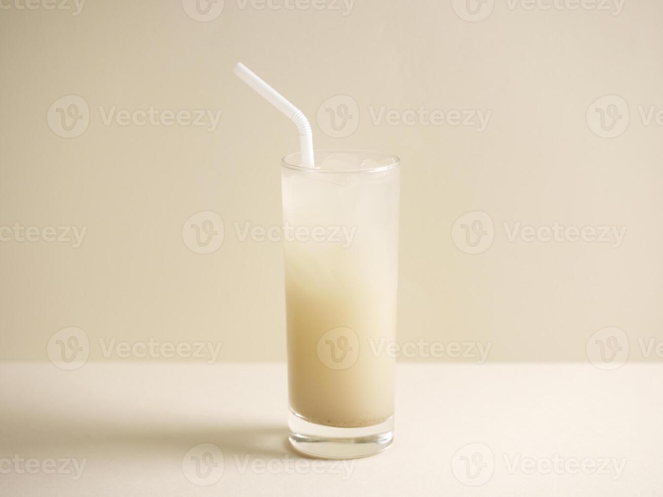 ein Glas von Gerste Wasser mit Stroh isoliert auf grau Hintergrund Seite Aussicht foto