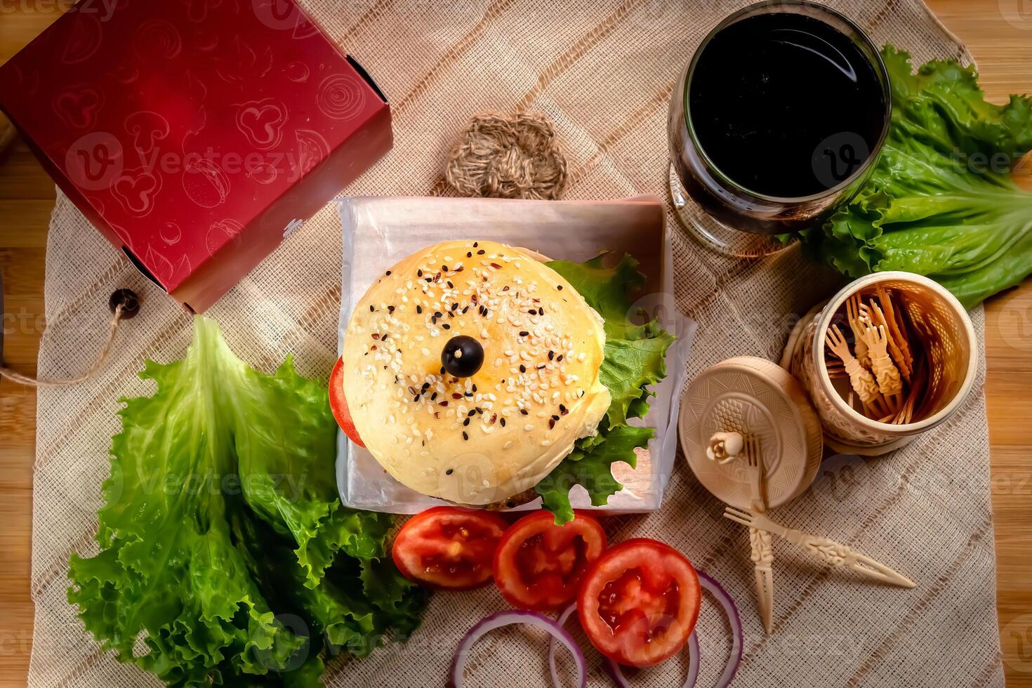 traditionell Rindfleisch Burger mit kalt trinken, Tomate Scheibe isoliert auf hölzern Tafel oben Aussicht auf Tabelle schnell Essen foto