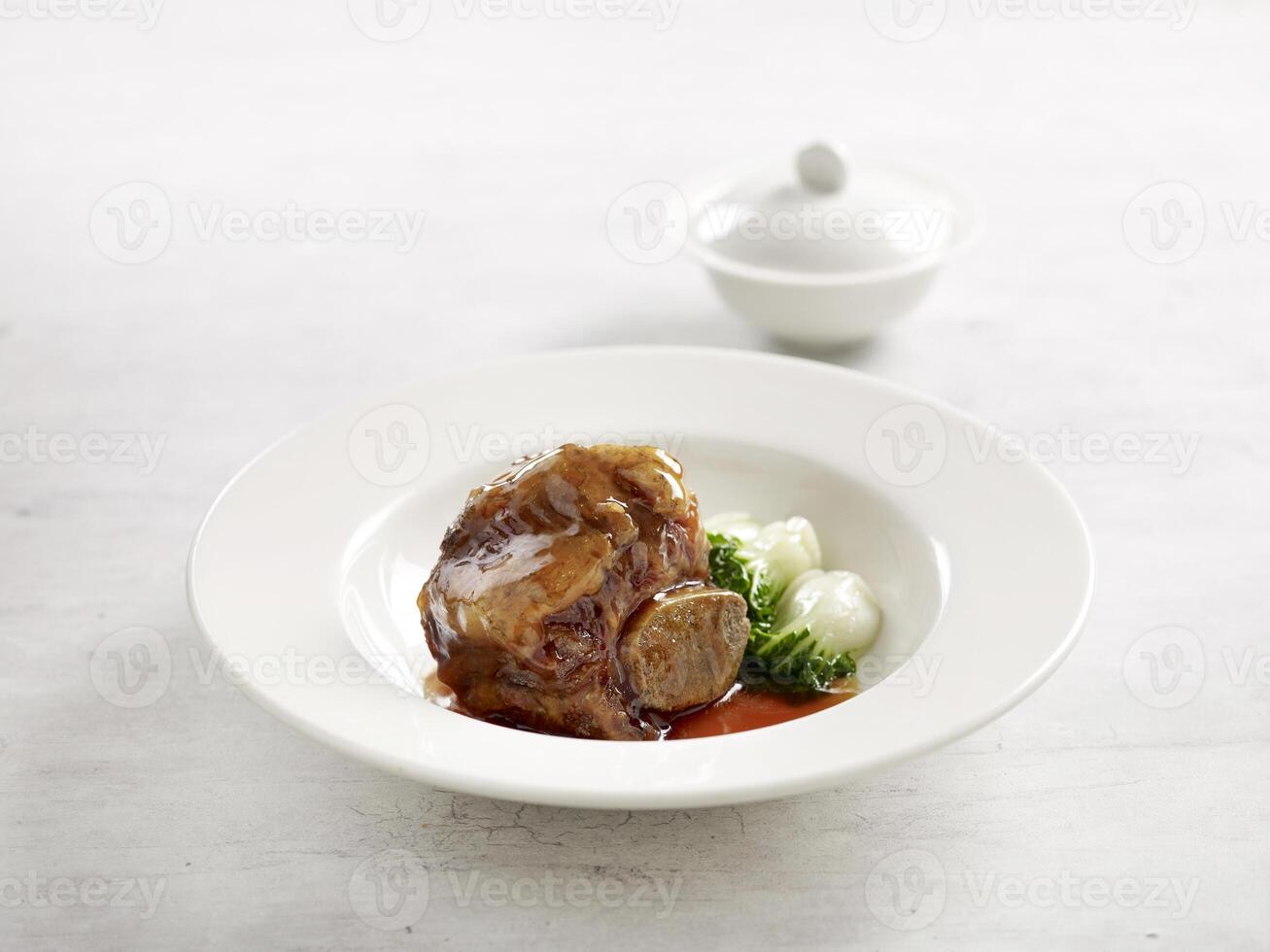 geschmort uns Angus Rindfleisch kurz Rippe im braun Soße serviert im ein Teller Seite Aussicht auf grau Marmor Hintergrund USA Essen foto