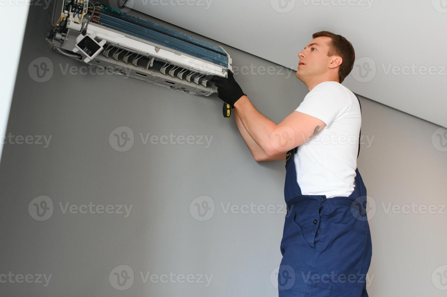 Techniker reparieren Luft Conditioner auf das Mauer foto