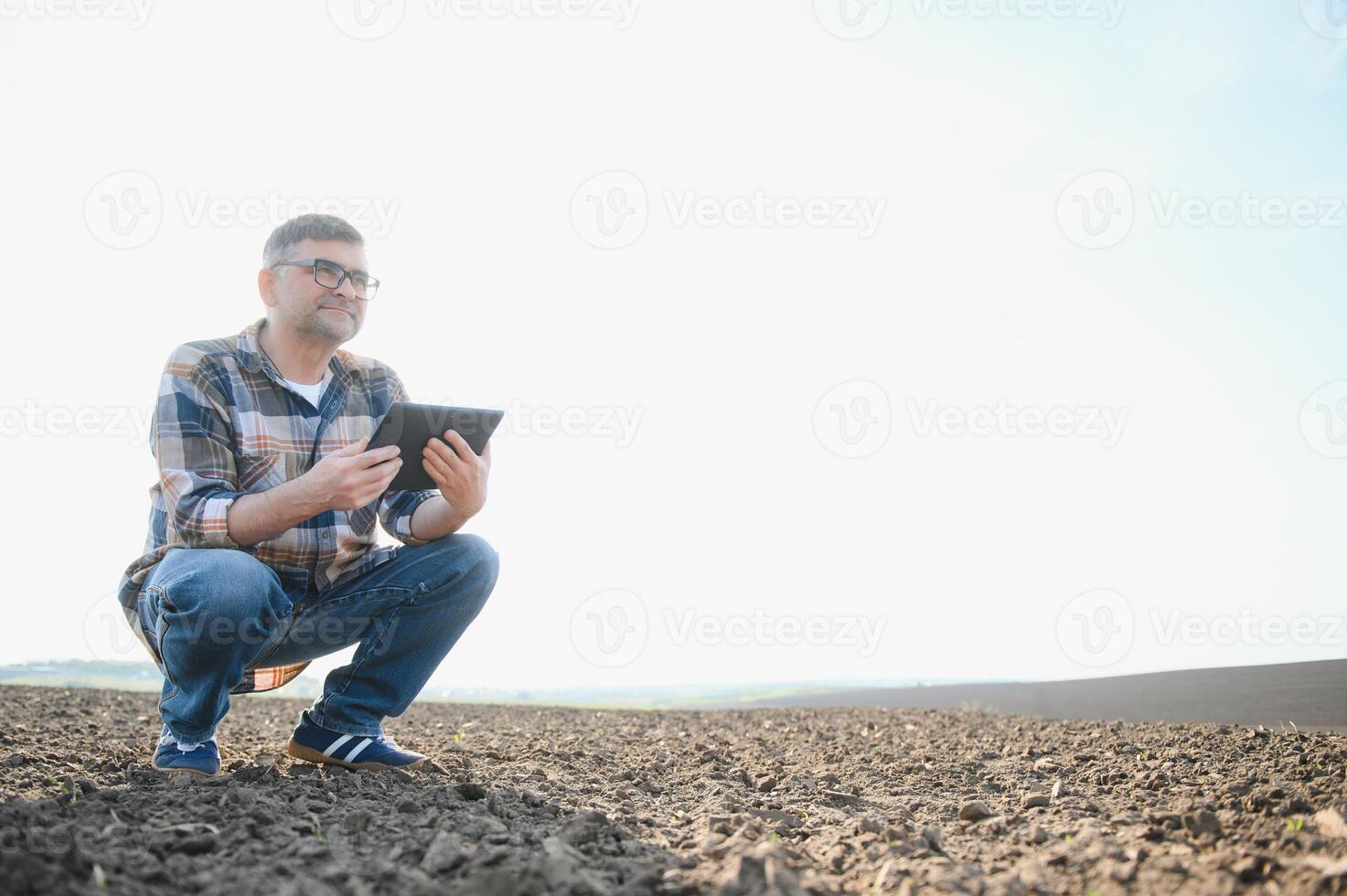 ein Farmer funktioniert im ein Feld gesät im Frühling. ein Agronom Spaziergänge das Erde, beurteilen ein gepflügt Feld im Herbst. Landwirtschaft. Clever Landwirtschaft Technologien. foto