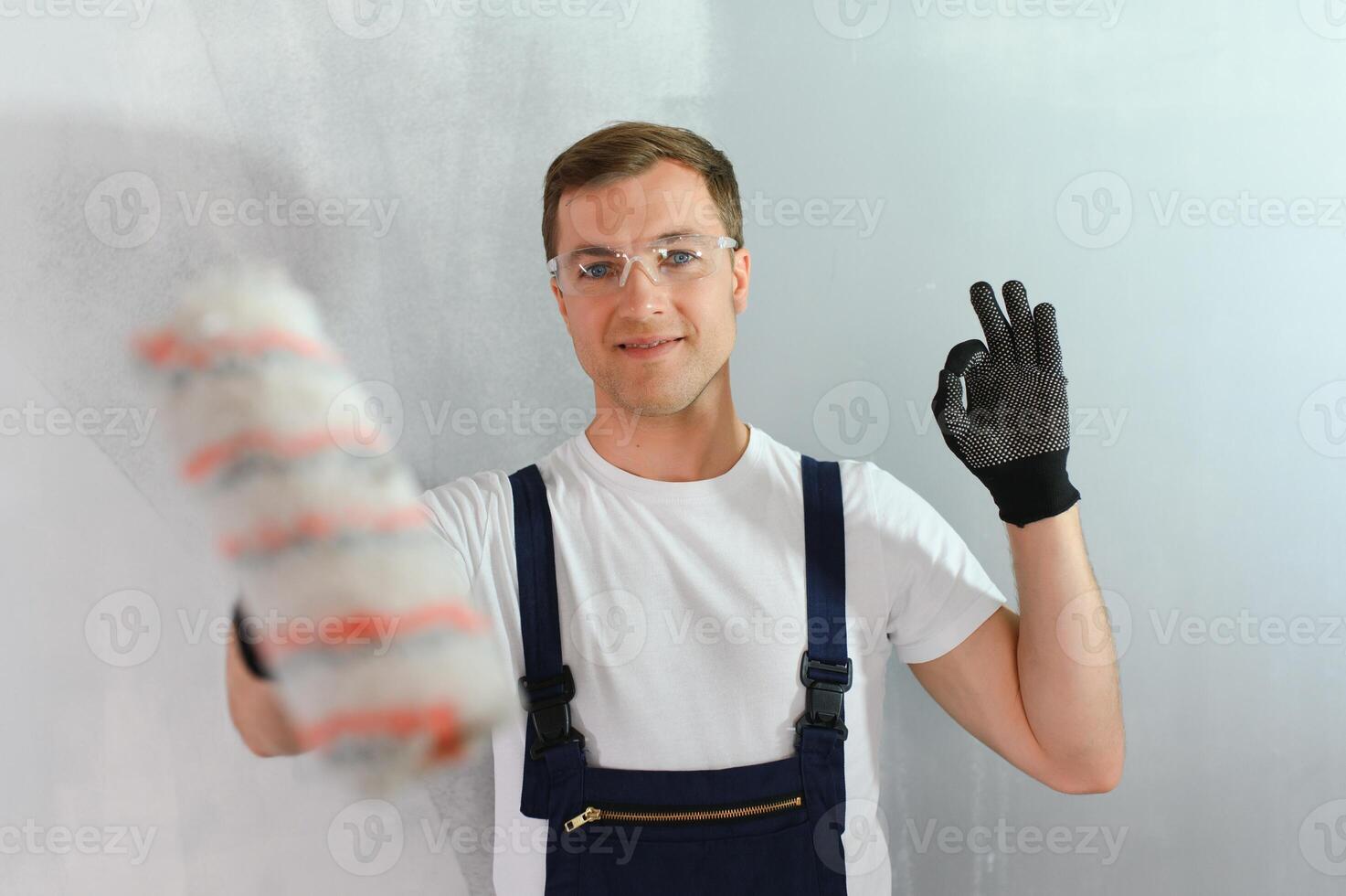 einer Maler mit Farbe Walze Herstellung Mauer Prime Glasur beim Zuhause Reparatur Renovierung arbeiten. foto