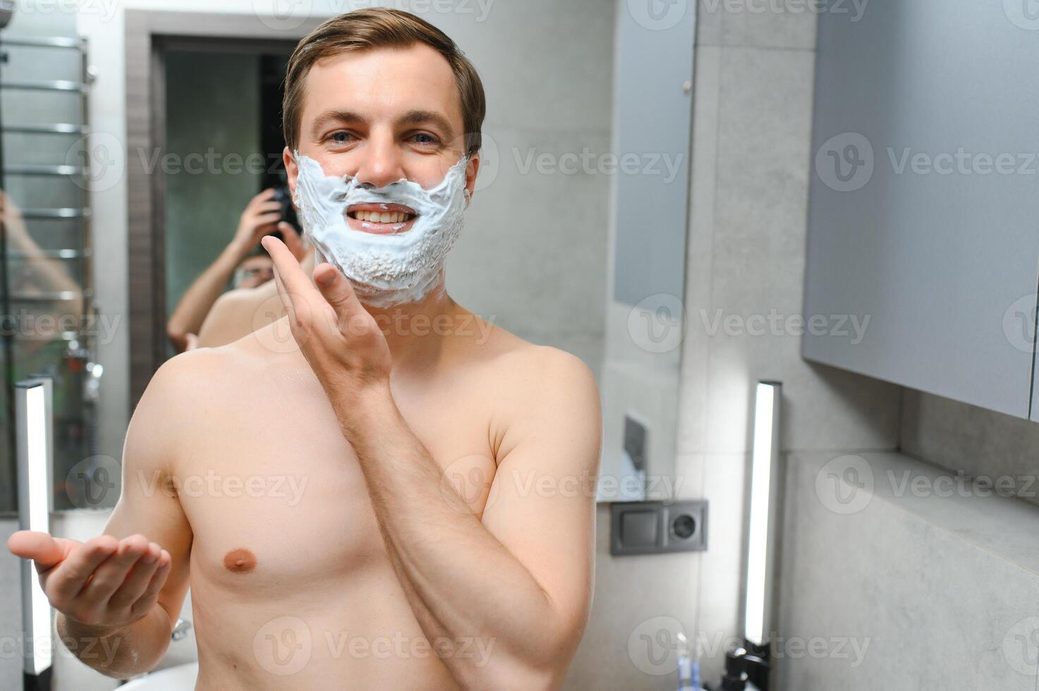 reifen gut aussehend Mann Rasieren im Vorderseite von Spiegel foto
