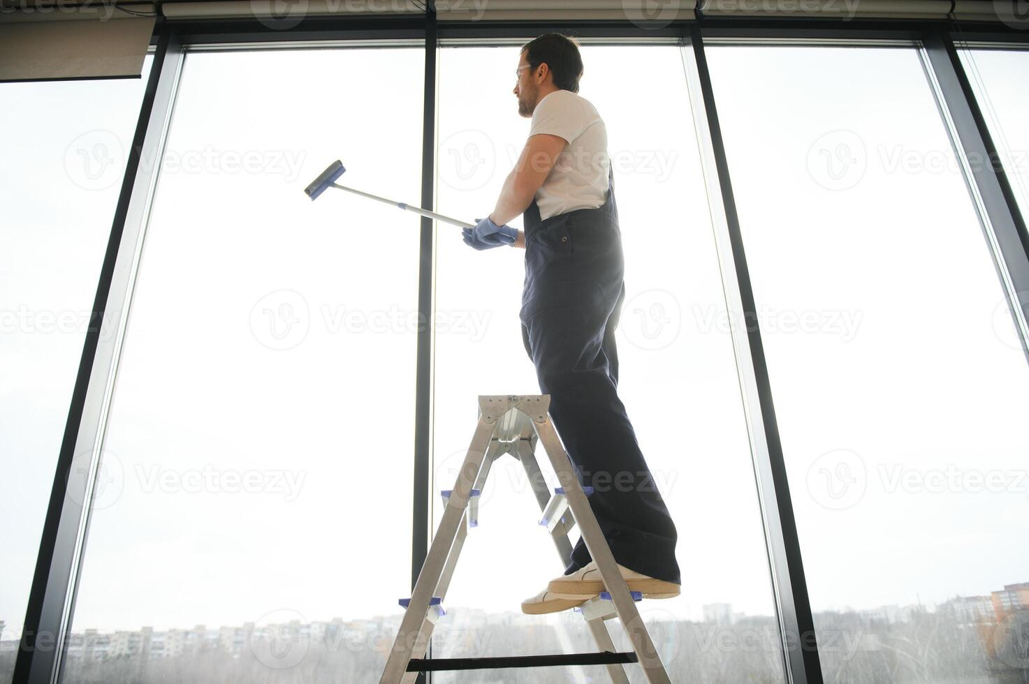 ein Mitarbeiter von ein Fachmann Reinigung Bedienung wäscht das Glas von das Fenster von das Gebäude. Vitrine Reinigung zum Geschäfte und Unternehmen. foto