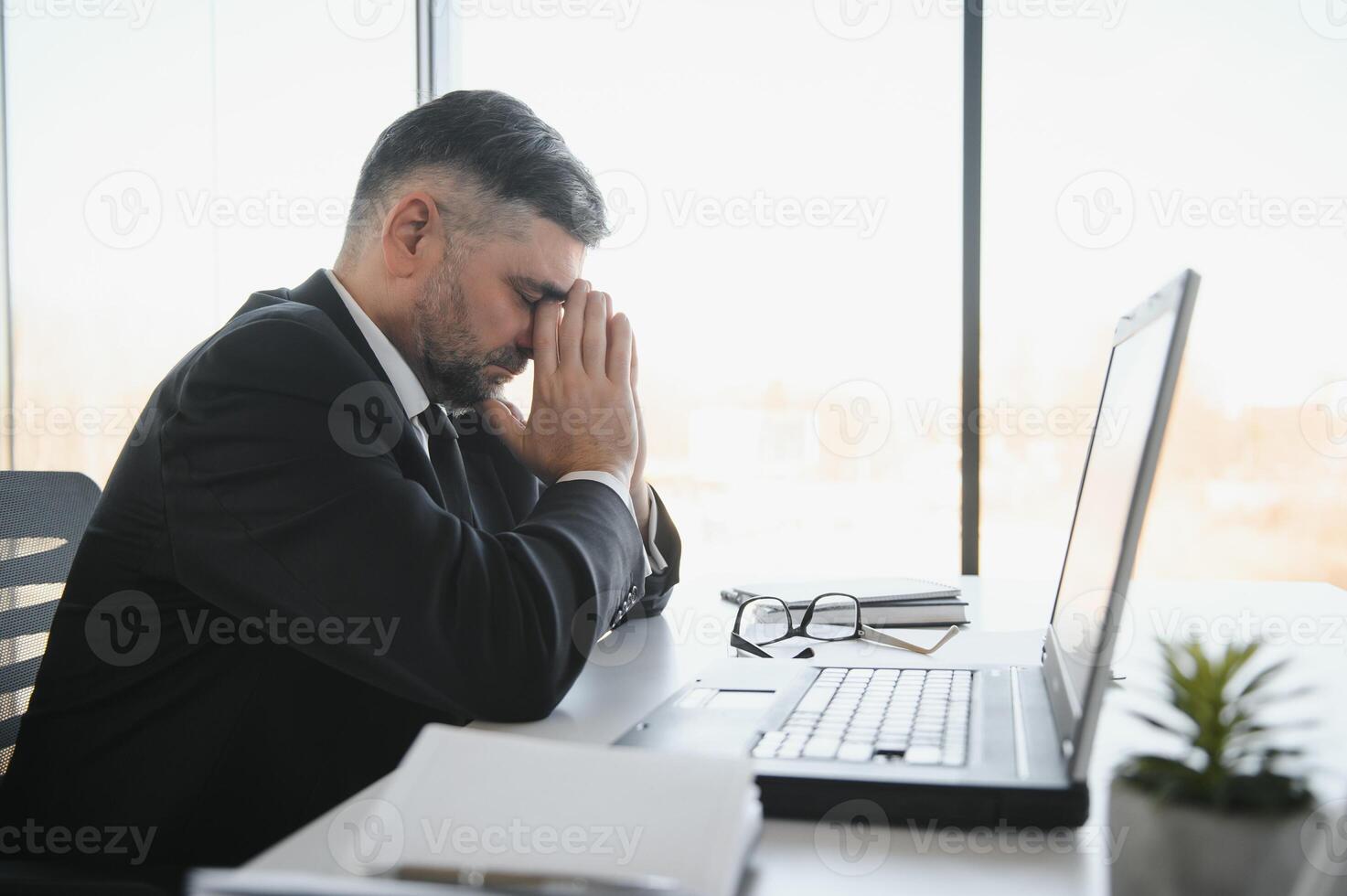 müde betont Büro Arbeiter Sitzung beim Schreibtisch und Denken, er ist Reiben seine Augen und Gefühl erschöpft. foto