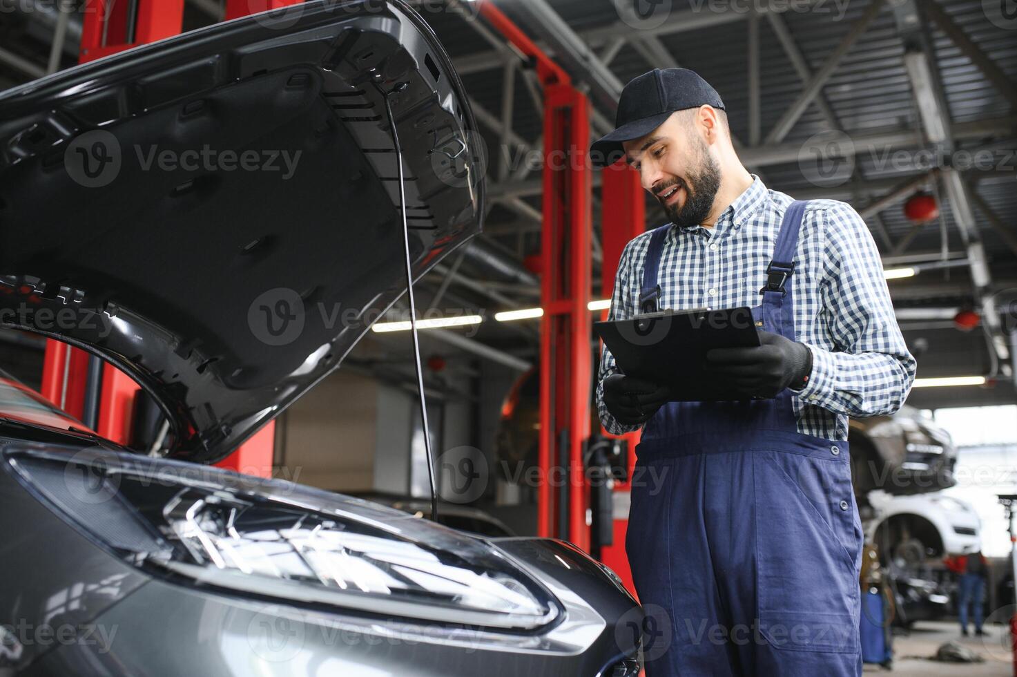 lächelnd Mechaniker Schreiben auf Zwischenablage beim das Reparatur Garage foto