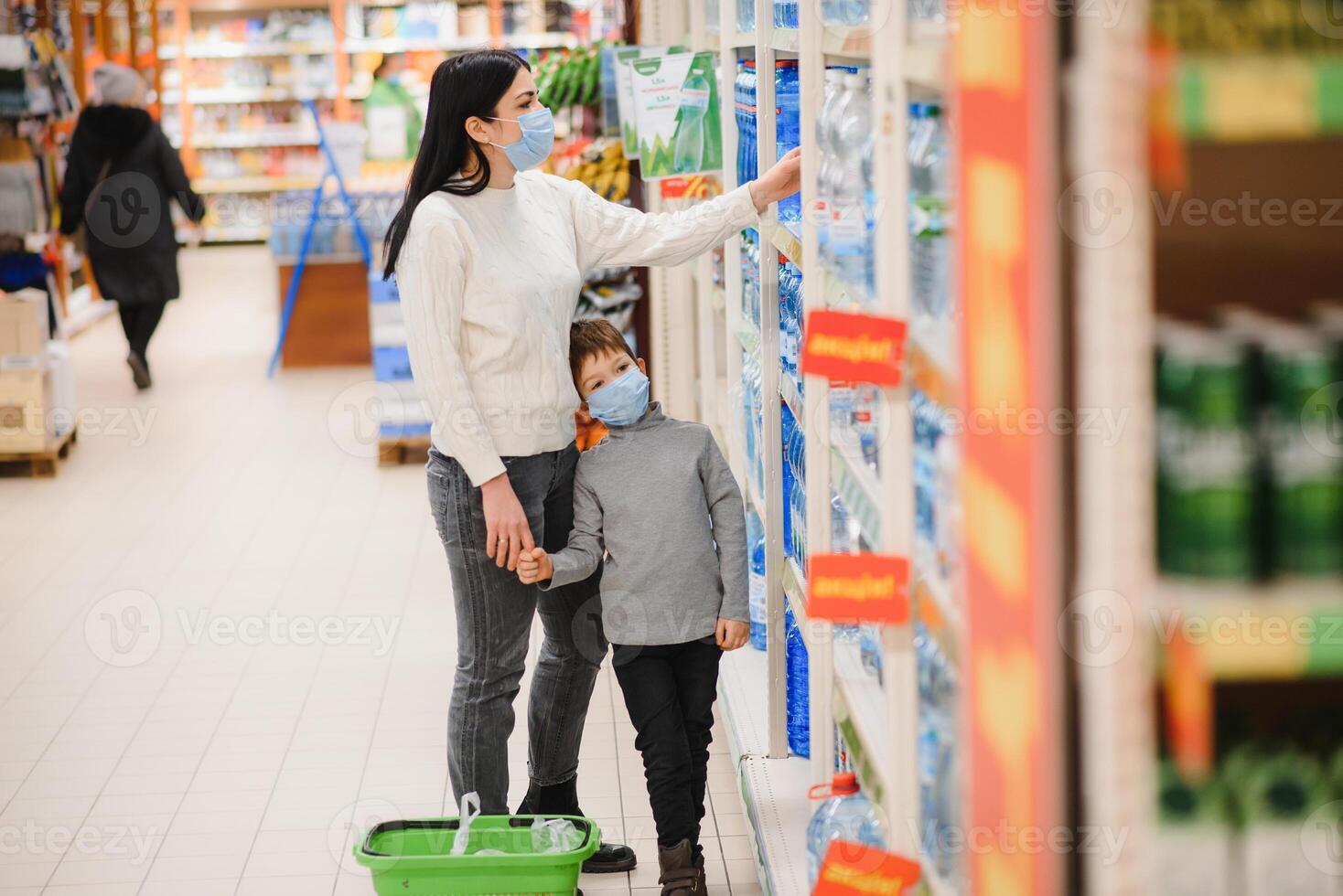 jung Frau und ihr Kind tragen schützend Gesicht Masken Geschäft ein Essen beim ein Supermarkt während das Coronavirus Epidemie oder Grippe Ausbruch. foto