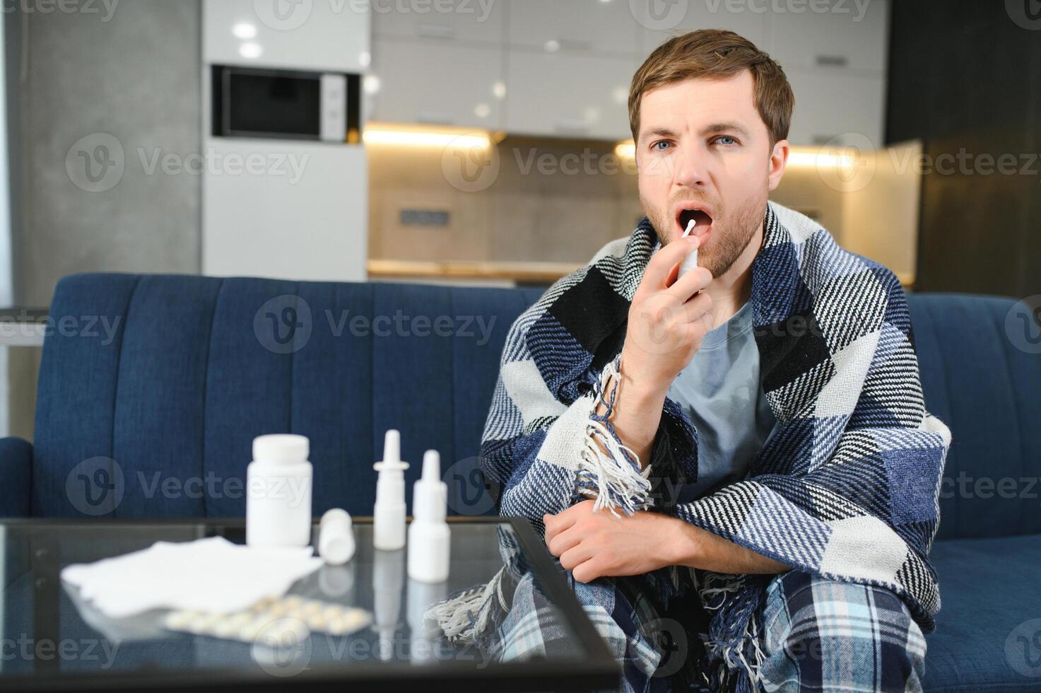 Schnupfen, Medizin und Gesundheitswesen Konzept - - krank Mann im Decke mit Oral sprühen beim heim. foto