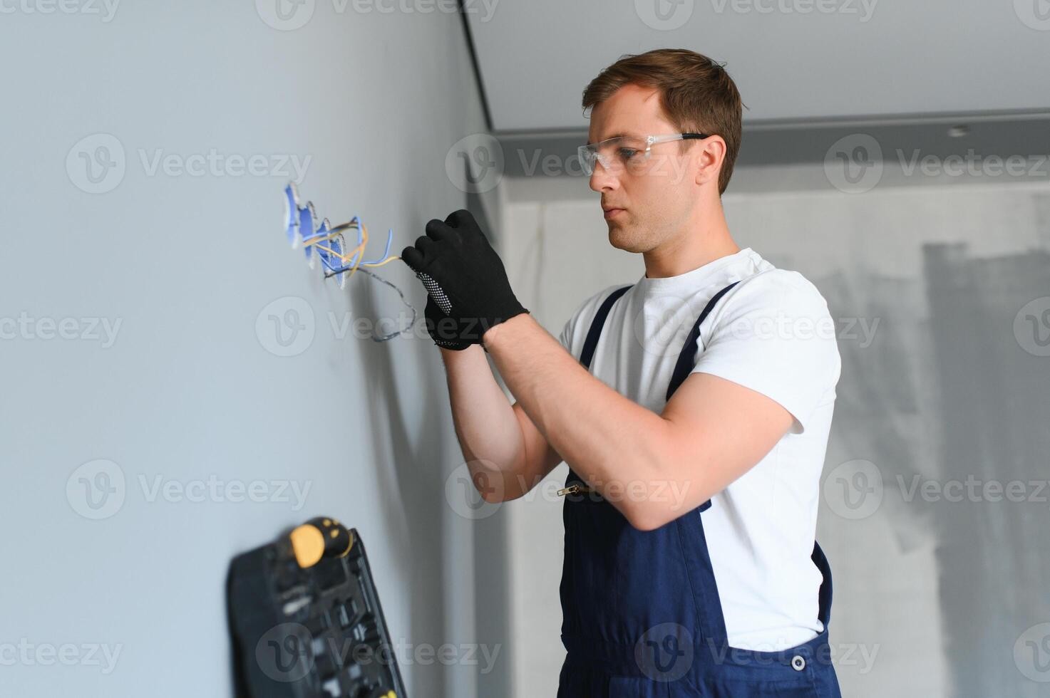 Elektriker beim Arbeit auf Schalter und Steckdosen von ein Wohn elektrisch System. foto