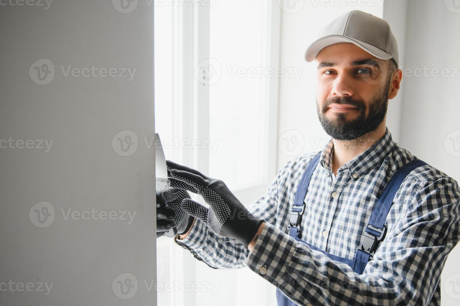 Stuckateur im Blau Arbeiten Uniform Verputzen das Mauer drinnen foto