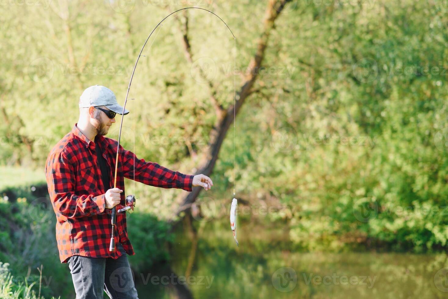 Fischer durch das Fluss mit ein Fang von Fisch. Mann Fischer hält im Hand Fisch. foto