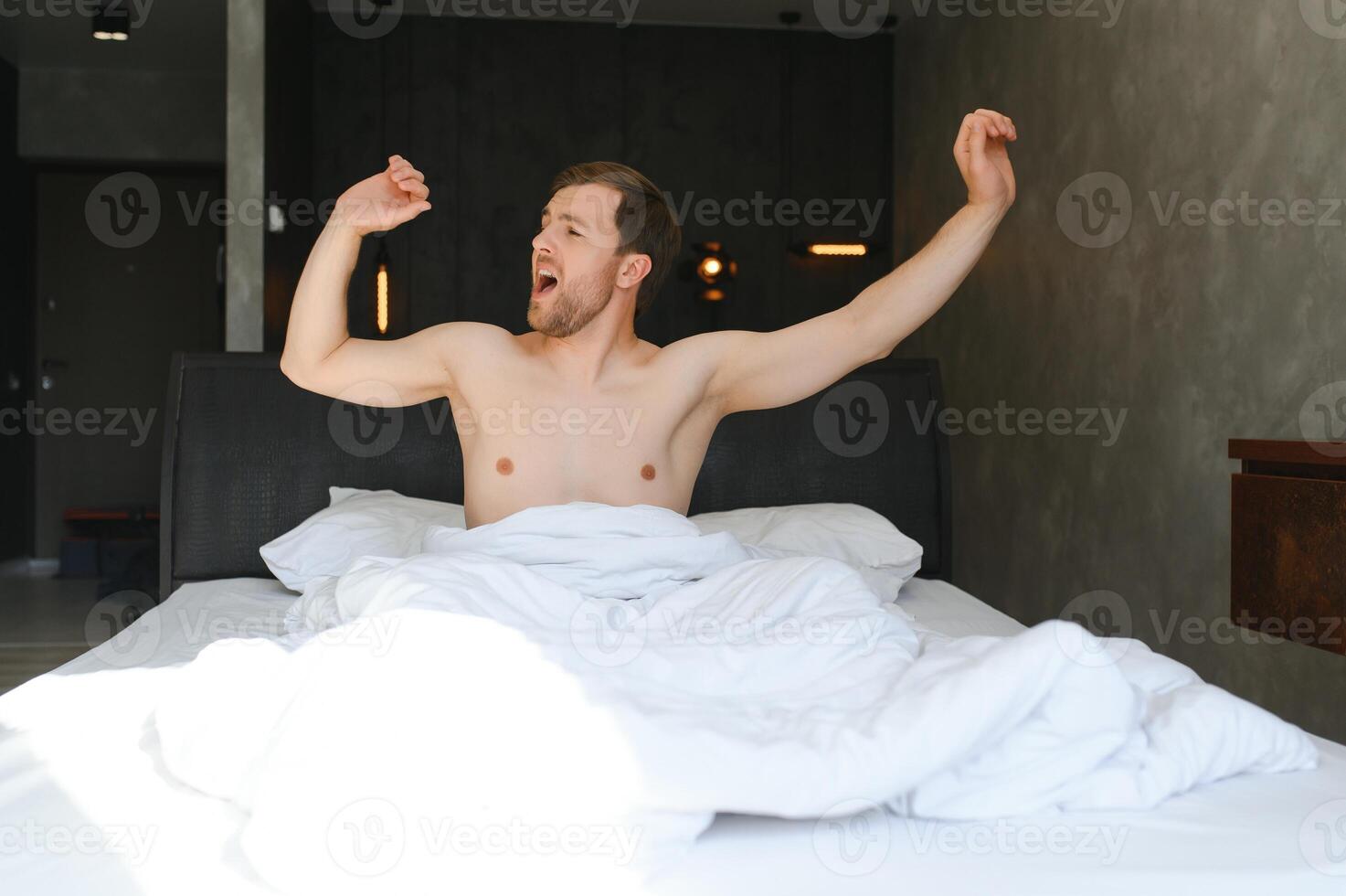 glücklich jung bärtig Mann ist entspannend auf das Bett beim Zuhause foto