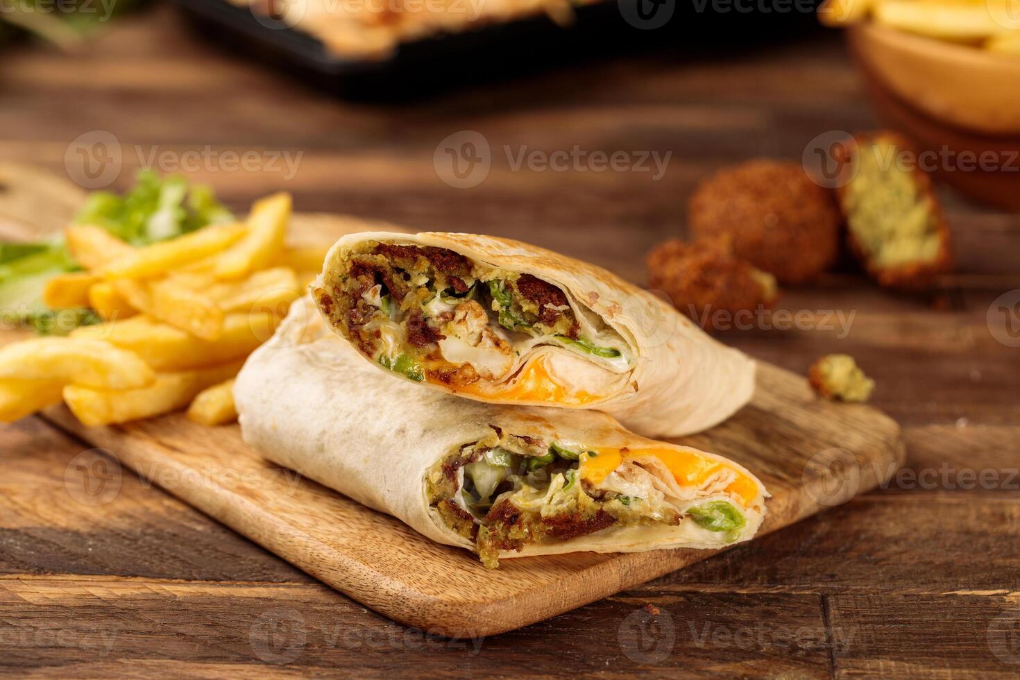 Falafel wickeln Döner mit Fritten serviert im ein Schneiden Tafel isoliert auf hölzern Tabelle Hintergrund Seite Aussicht von Fast Food foto