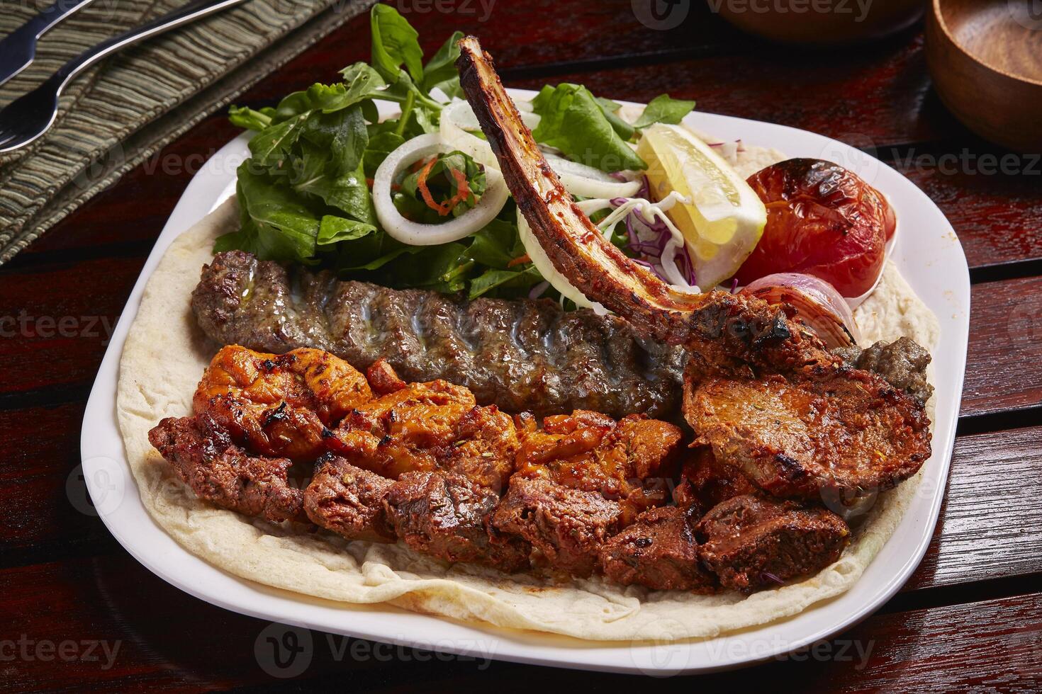 würzig gemischt Grills Teller mit Tikka boti Kebab, Salat, Zitrone und Brot serviert im Gericht isoliert auf Tabelle Seite Aussicht von Mitte Osten Essen foto