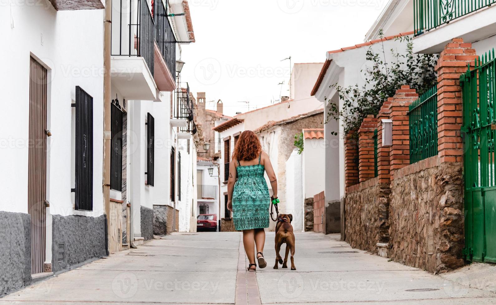 junge Frau, die mit Boxerhund die Straße entlang geht foto