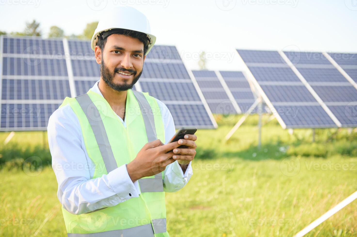 Porträt von jung indisch männlich Ingenieur Stehen in der Nähe von Solar- Tafeln, mit klar Blau Himmel Hintergrund, verlängerbar und sauber Energie. Fertigkeit Indien, Kopieren Raum. foto