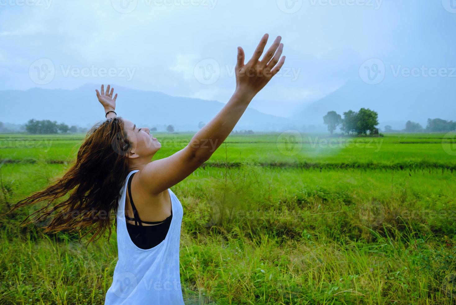 asiatische frauen reisen im urlaub entspannen. das mädchen lächelte glücklich und genoss den regen, der fiel. Reisen in Länder, grüne Reisfelder, Reisen durch Thailand. foto