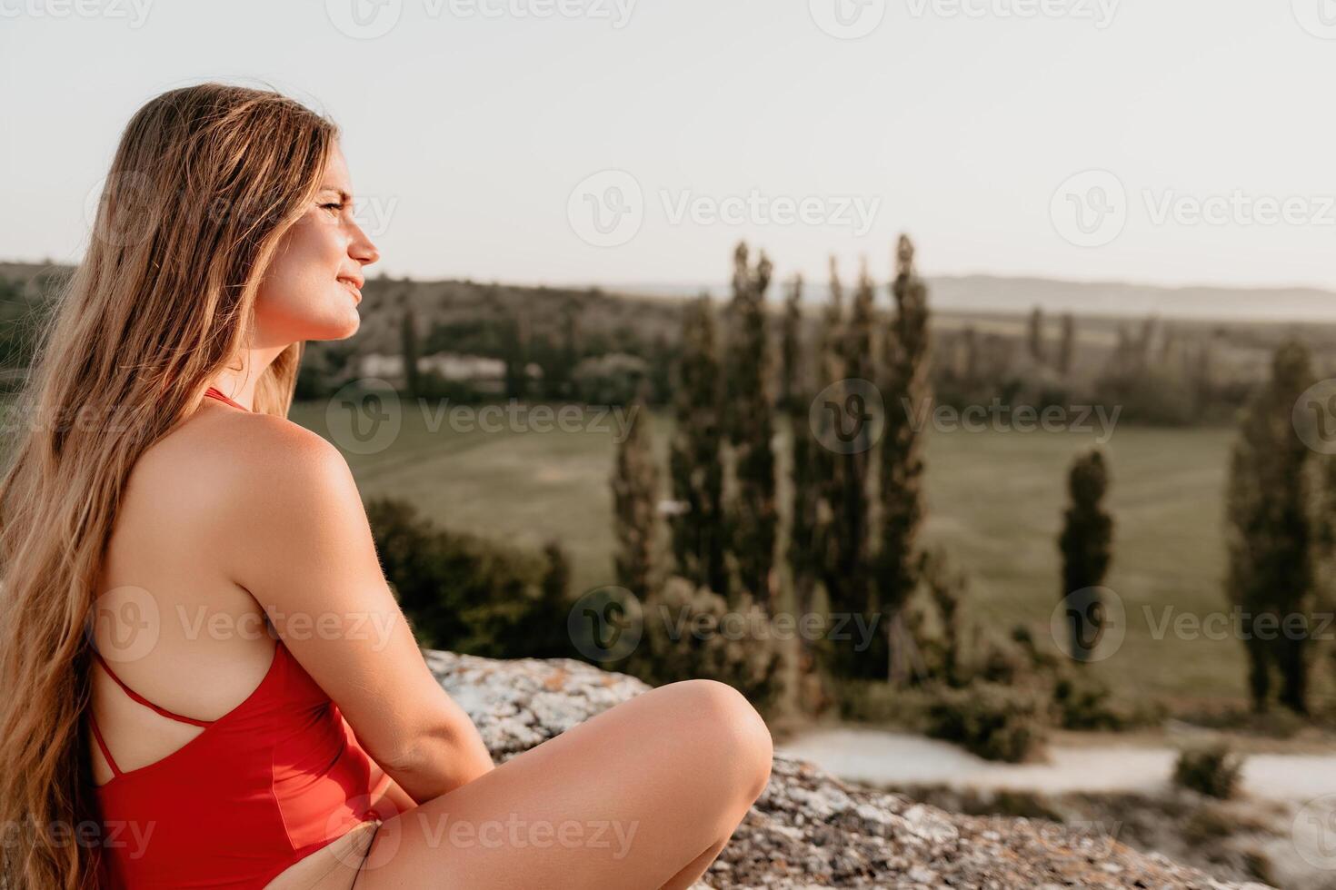 Gut suchen Mitte alt Frau mit lange Haar, Fitness Lehrer im Gamaschen und Spitzen tun Dehnen und Pilates auf das Felsen in der Nähe von Wald. weiblich Fitness Yoga Routine Konzept. gesund Lebensstil foto