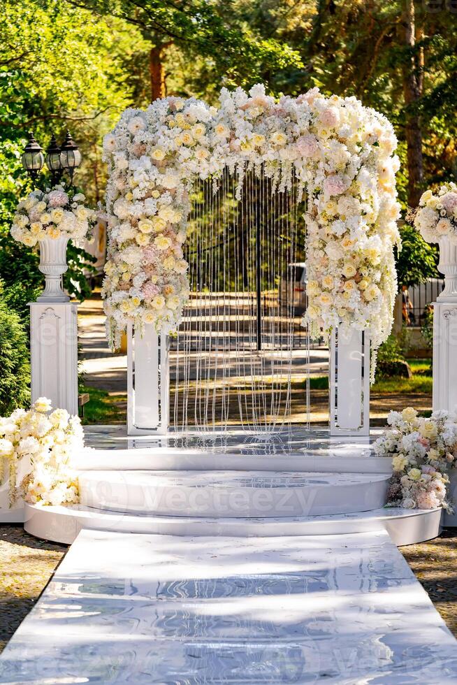 Hochzeit Zeremonie Dekoration. Weiß Bogen mit Blumen. Grün Park Hintergrund. Sommer- Party. foto