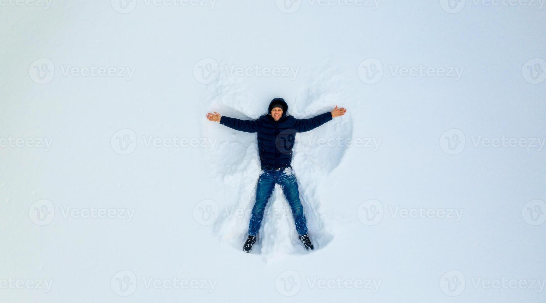 ein jung Kind spielen im das Schnee Herstellung ein Winkel. Junge Theaterstücke im Weiß Schnee. Aussicht von das oben. foto