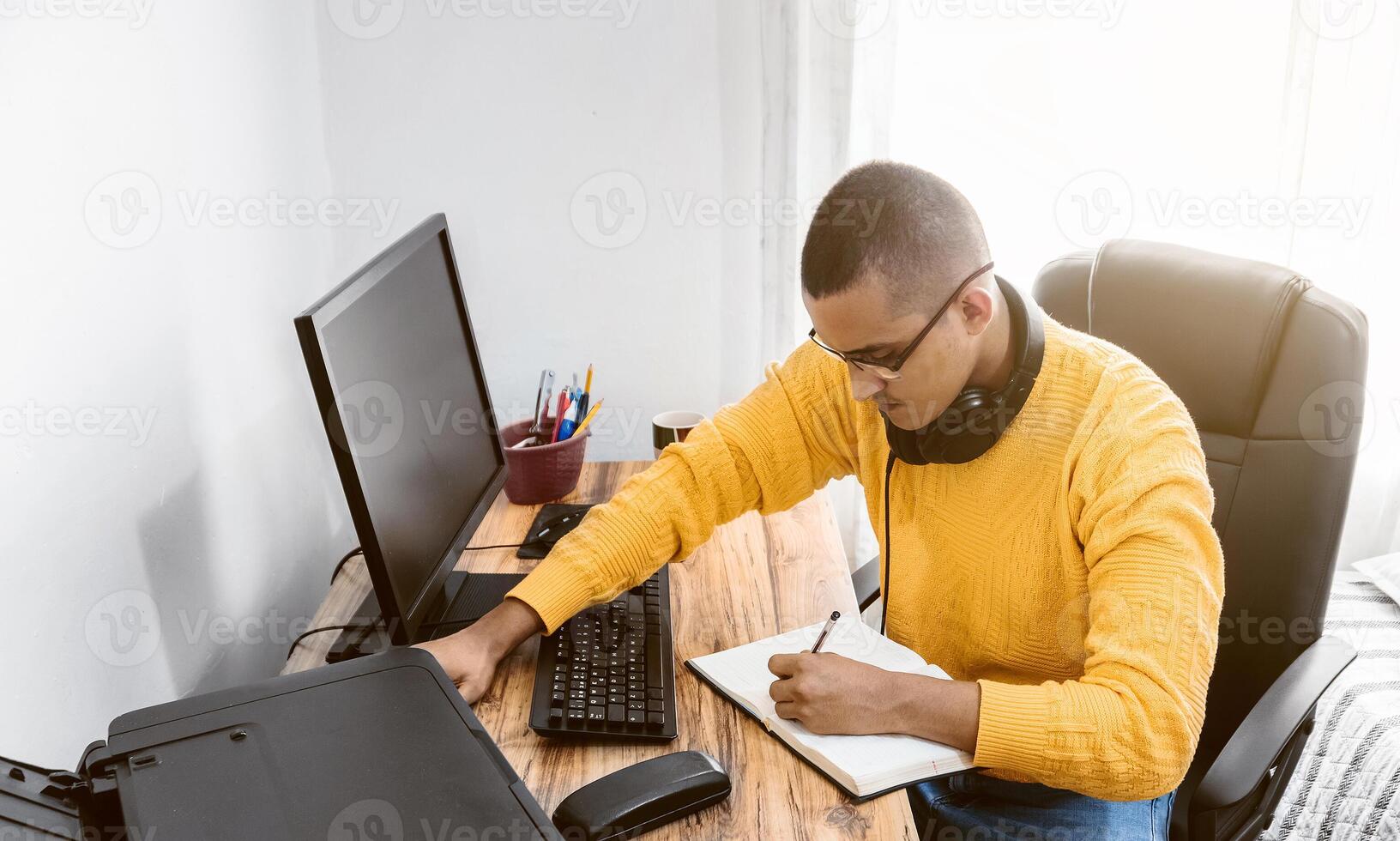 Latein amerikanisch jung Erwachsene Mann Schüler oder Unternehmer Schreiben im ein Notizblock oder Notizbuch beim seine Schreibtisch. foto