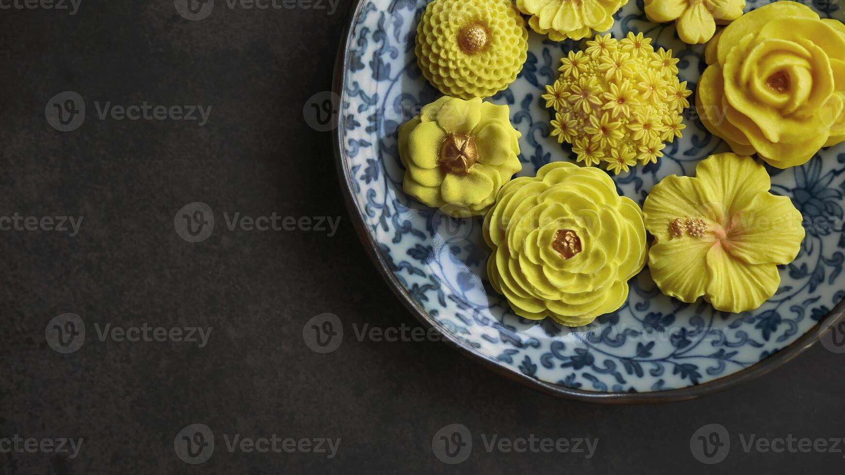 thailändisch Dessert im verschiedene Blume geformt, warm Farbe Ton, Gelb Mango Geschmack im Antiquität Muster Platte, Sam schwenken nee traditionell thailändisch Handwerk Snack im dunkel Hintergrund foto