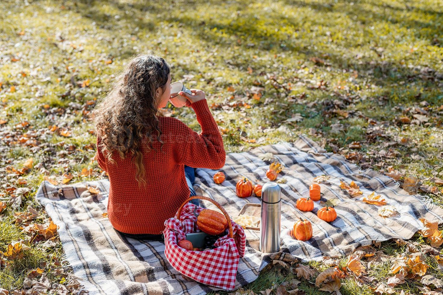 schöne Frau im roten Pullover bei einem Picknick in einem herbstlichen Wald foto