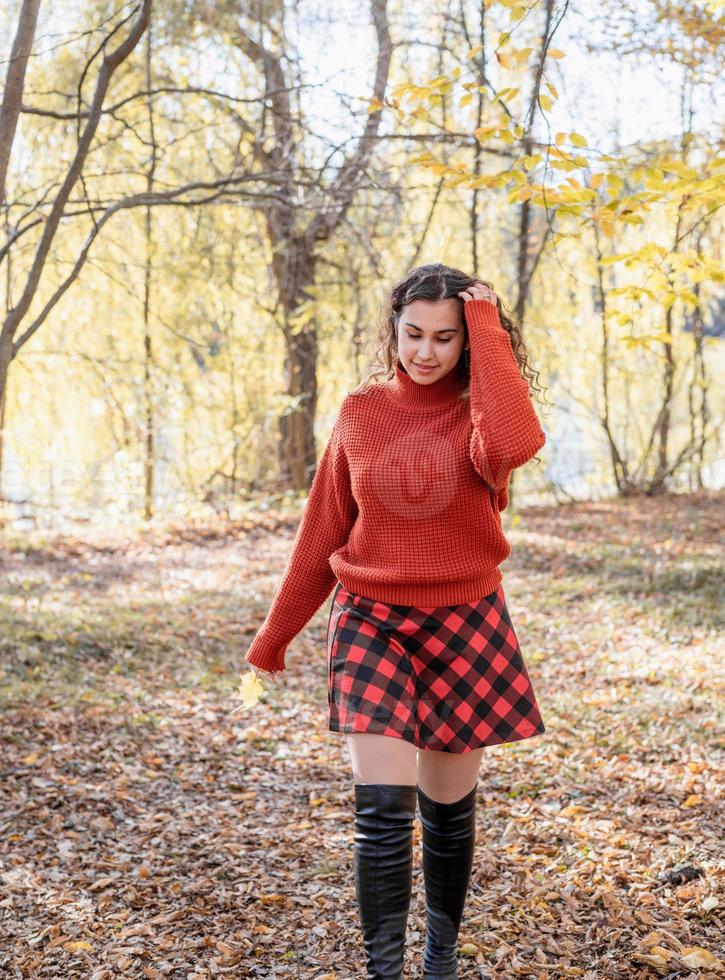 junge glückliche Frau, die im Herbstwald geht foto