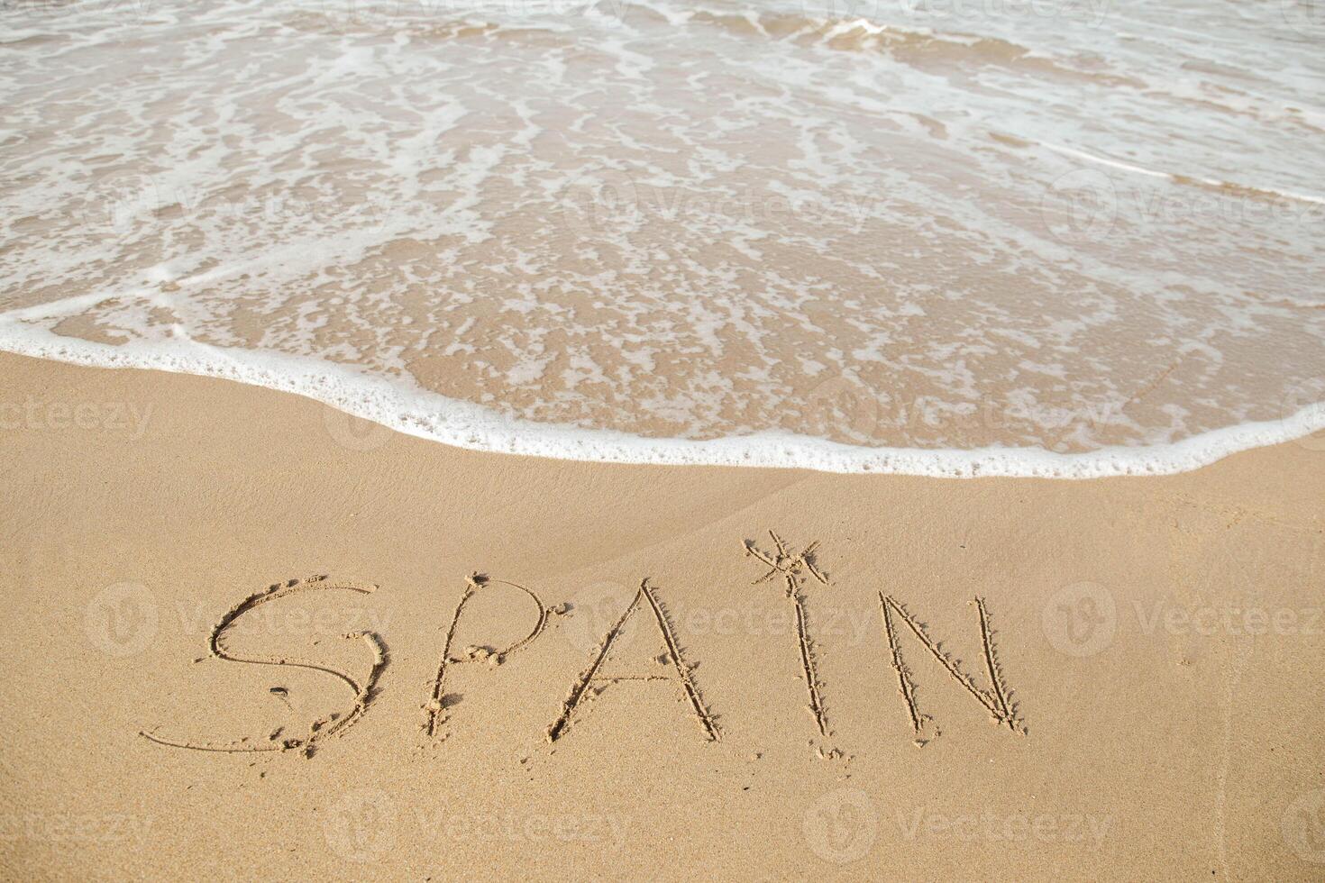 Spanien Beschriftung auf das Strand mit Welle und klar Blau Meer. Briefe Spanien auf das Meer Ufer, Botschaft handgeschrieben im das golden Sand auf schön Strand Hintergrund. Ferien im Spanien Konzept. hoch Qualität Foto