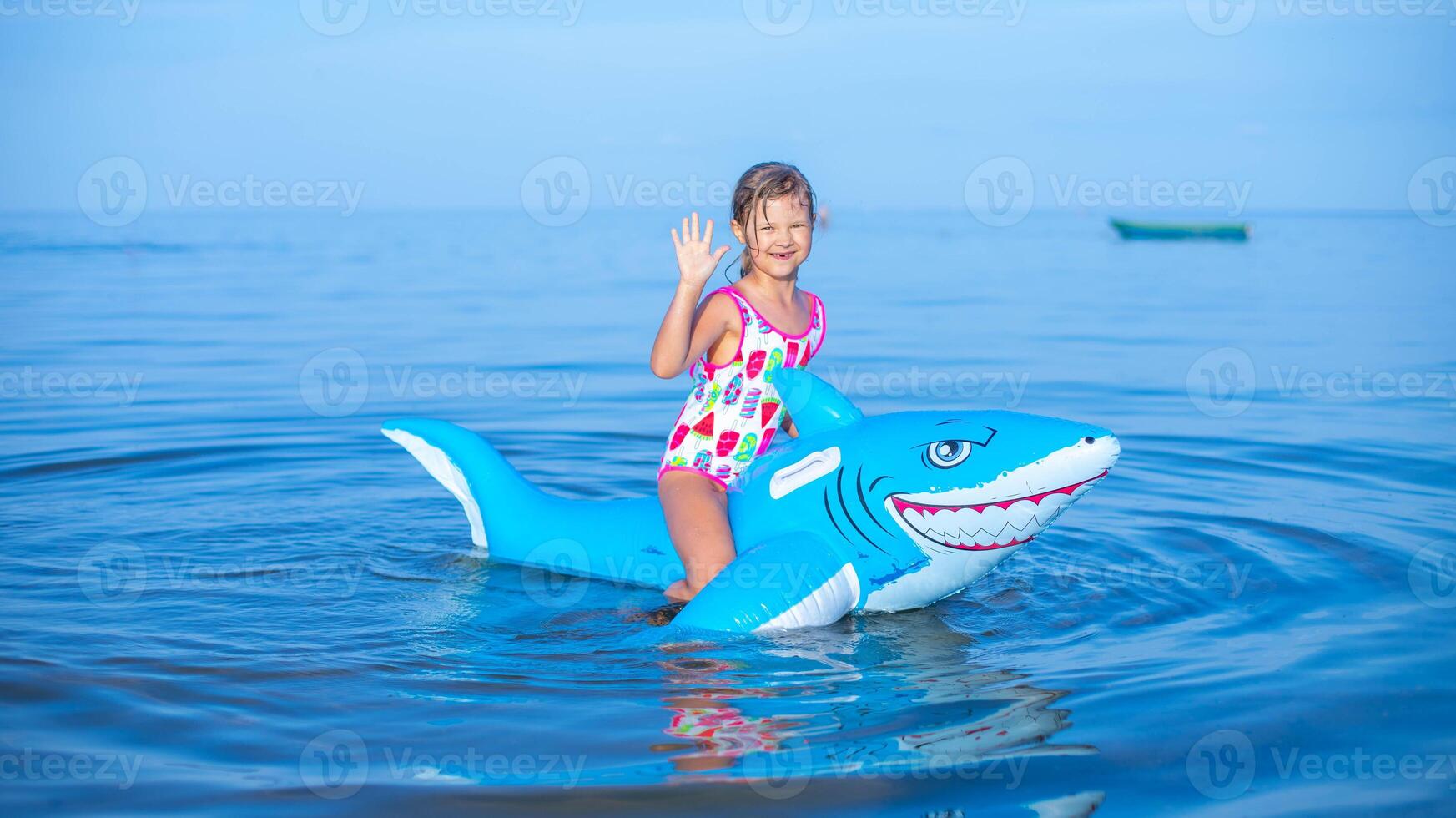 glücklich Mädchen von europäisch Aussehen Alter von 7 Schwimmen auf ein aufblasbar groß Hai Spielzeug im das Meer.Familie Sommer- Berufung Konzept. foto