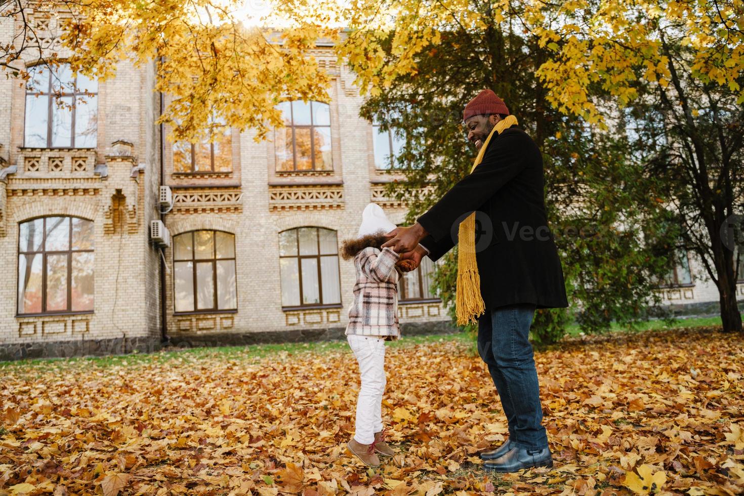 schwarzer Großvater und Enkelin machen Spaß beim gemeinsamen Spielen im Herbstpark foto
