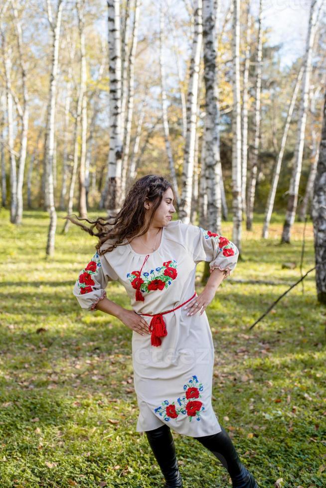 schöne Frau in ukrainischer Tracht, die im Wald tanzt foto