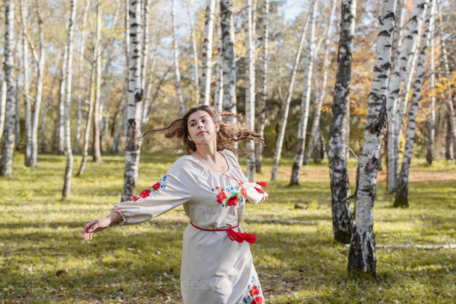 schöne Frau in ukrainischer Tracht, die im Wald tanzt foto