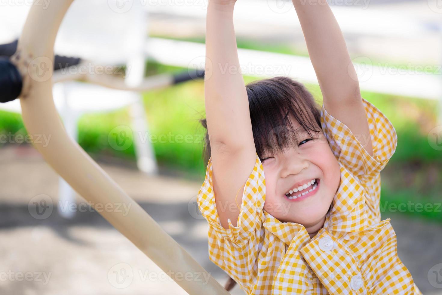 glückliche Kinderübung auf dem Spielplatz. asiatische Mädchen, die gelbe Hemden tragen, sind glückliches süßes Lächeln. gesundes Kind ist 5 Jahre alt. Nahaufnahme. foto