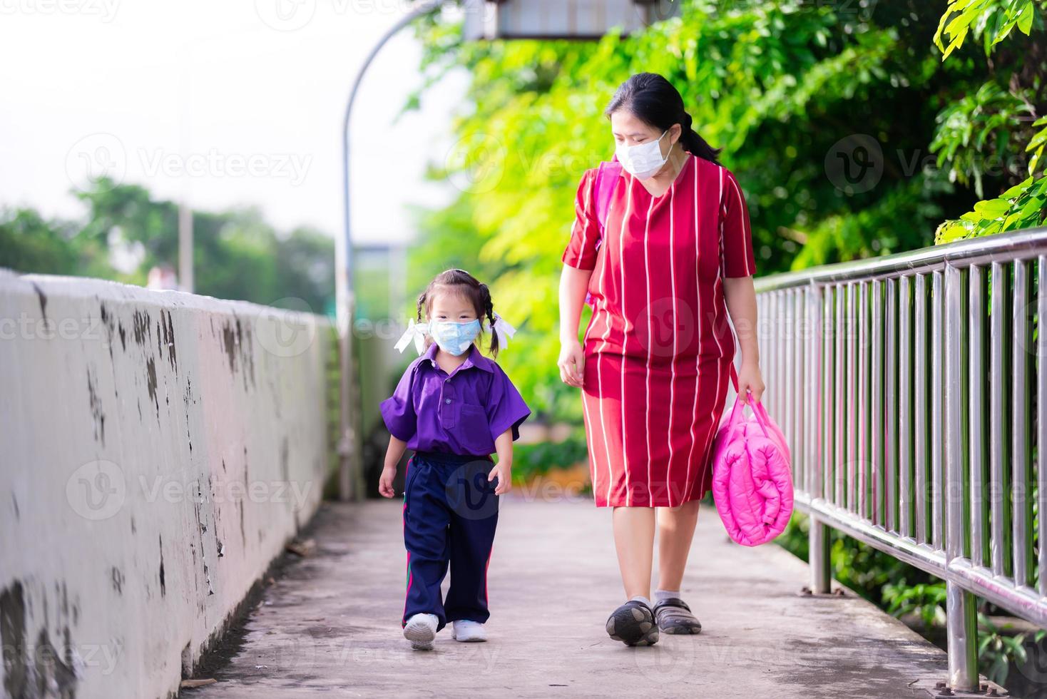 Familie trägt Stoffmasken. Mutter mit rosa Tochter Matratzentasche ging zur Schule. Familien schützen sich vor der Coronavirus-Erkrankung und am 2.5 durch das Tragen von Masken im Freien. neues normales Konzept. foto