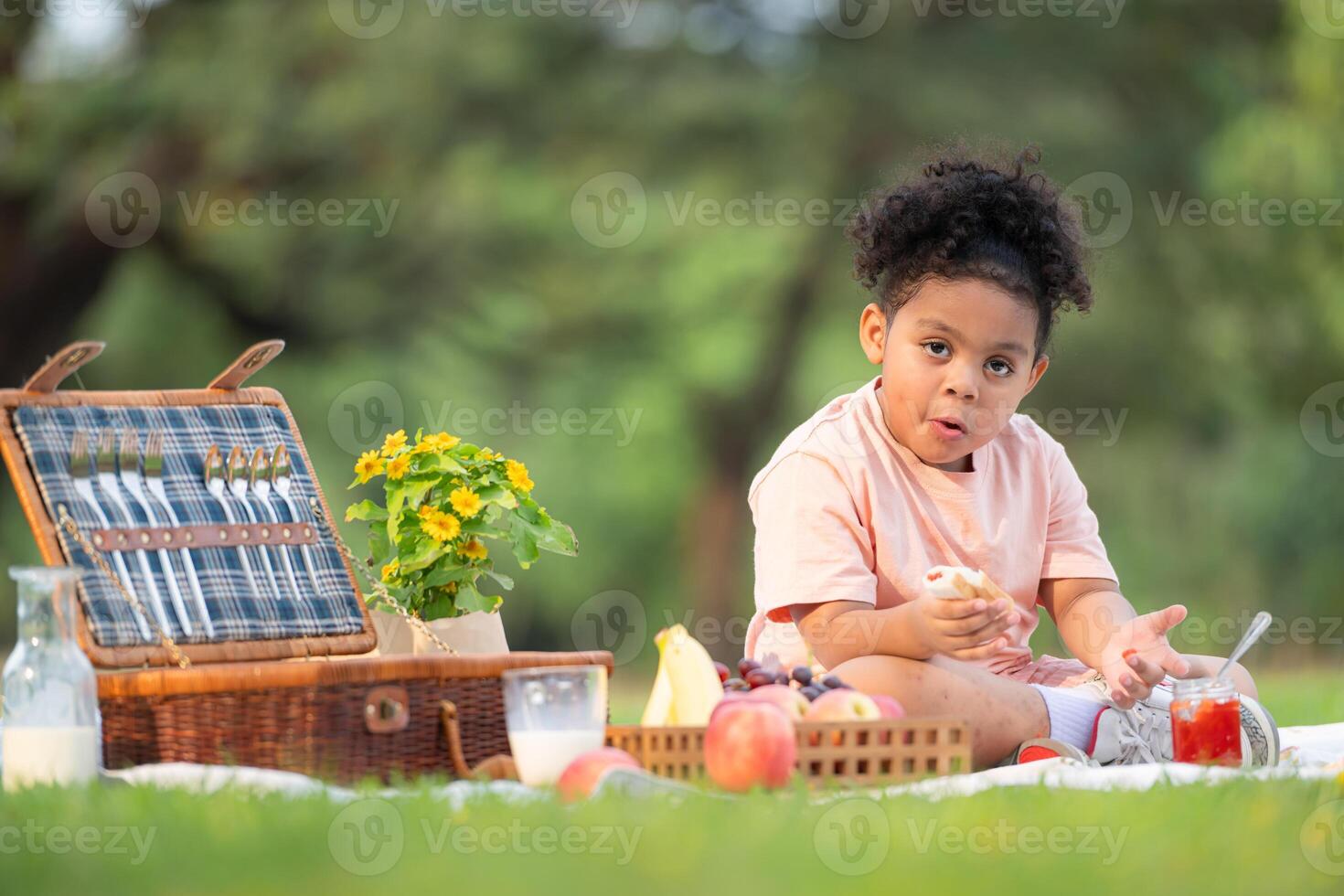 glücklich Familie genießen ein Picknick im das Park, mit Kind Essen Marmelade brot, umgeben durch Natur foto