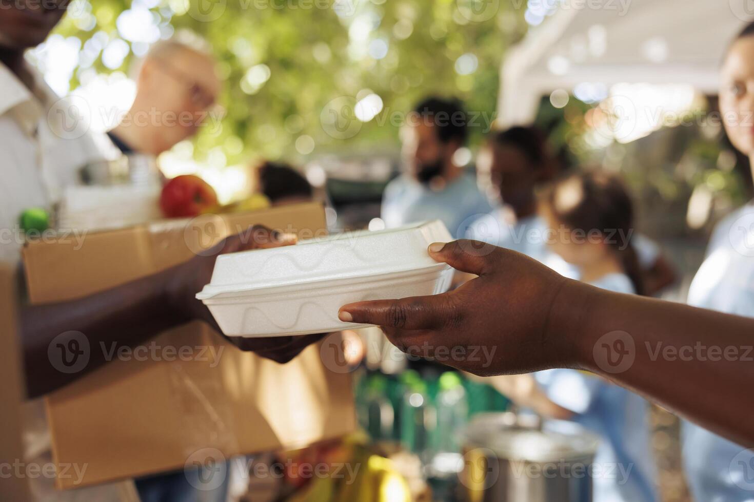 Freiwillige von afrikanisch amerikanisch Abstammung bietet an warm Mahlzeit zu ein verarmt und hungrig Individuell. Foto Fokus auf das weniger glücklich Person Empfang kostenlos Essen von wohltätig Arbeiter.