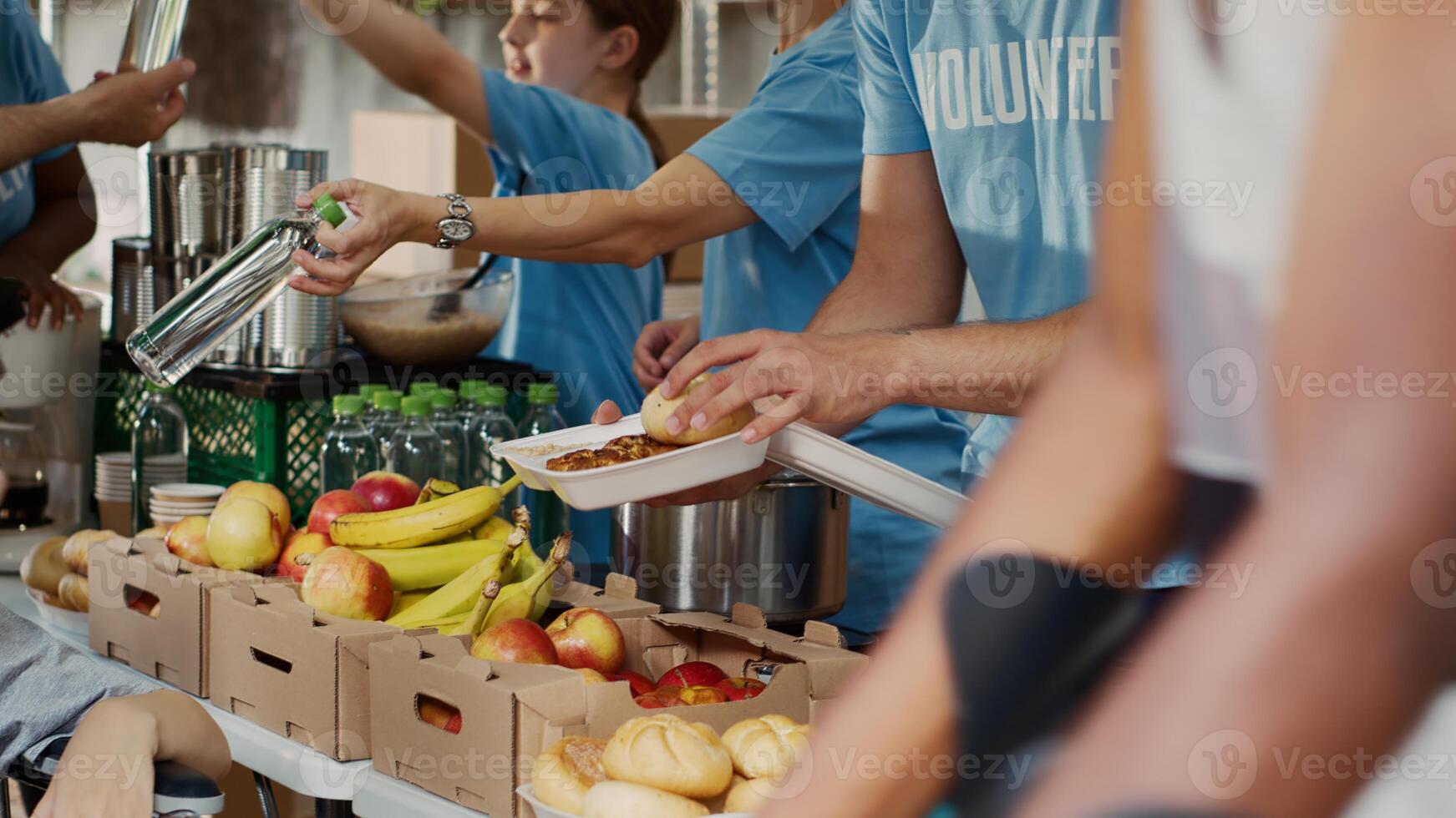 beim Essen Antrieb, Arm weiblich Rollstuhl Benutzer erhält kostenlos Essen und Bestimmungen. multiethnisch Freiwillige im Blau T-Shirt verteilen frisch Früchte und heiß Mahlzeiten zu weniger privilegiert. Nahaufnahme, Stativ. foto