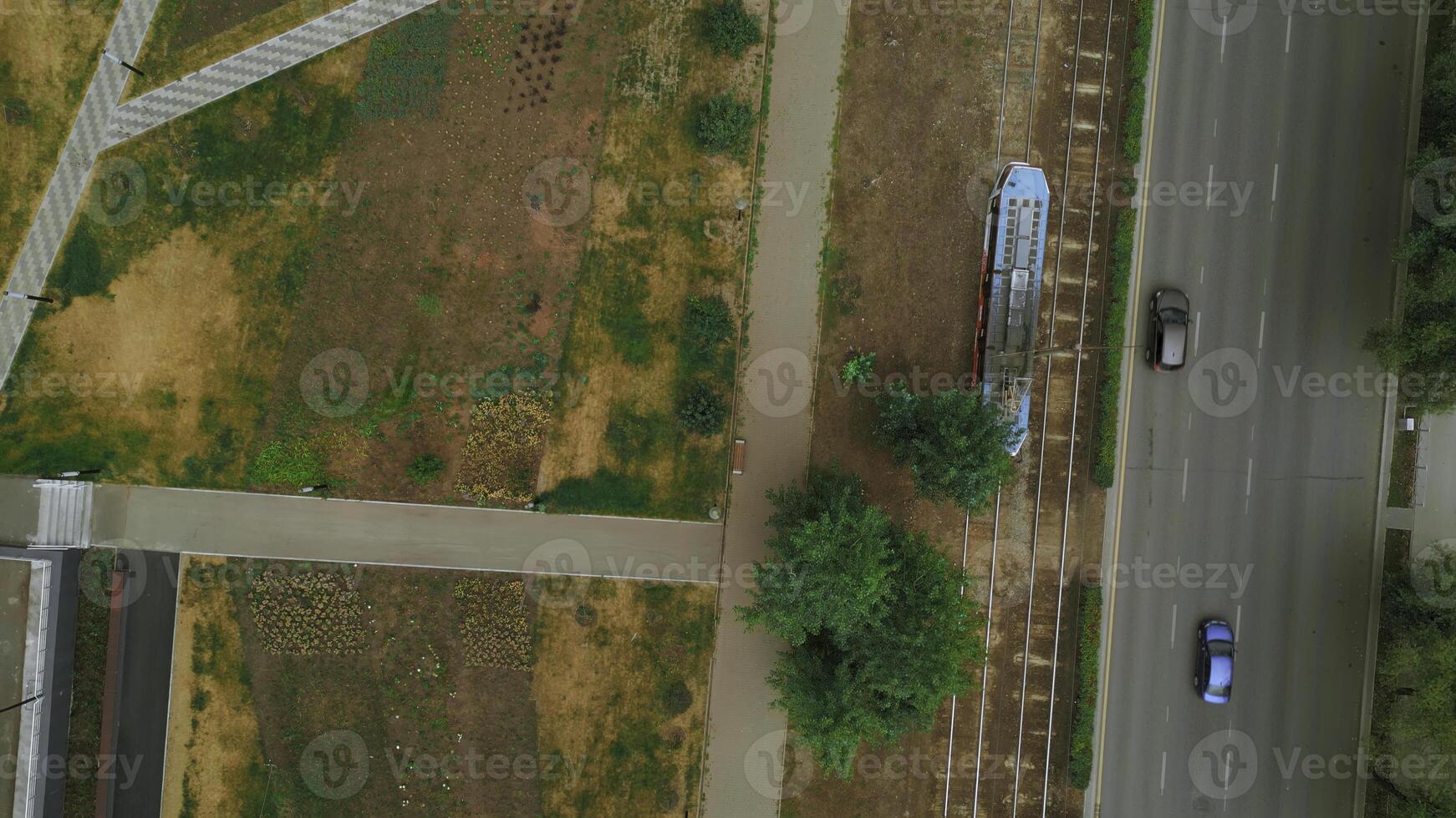 oben Aussicht von modern Straßenbahn im Stadt mit Park. Clip. Straßenbahn im Bewegung auf Schienen im Stadt im Sommer. Straßenbahn Fahrten beim Park Gasse im Stadt foto