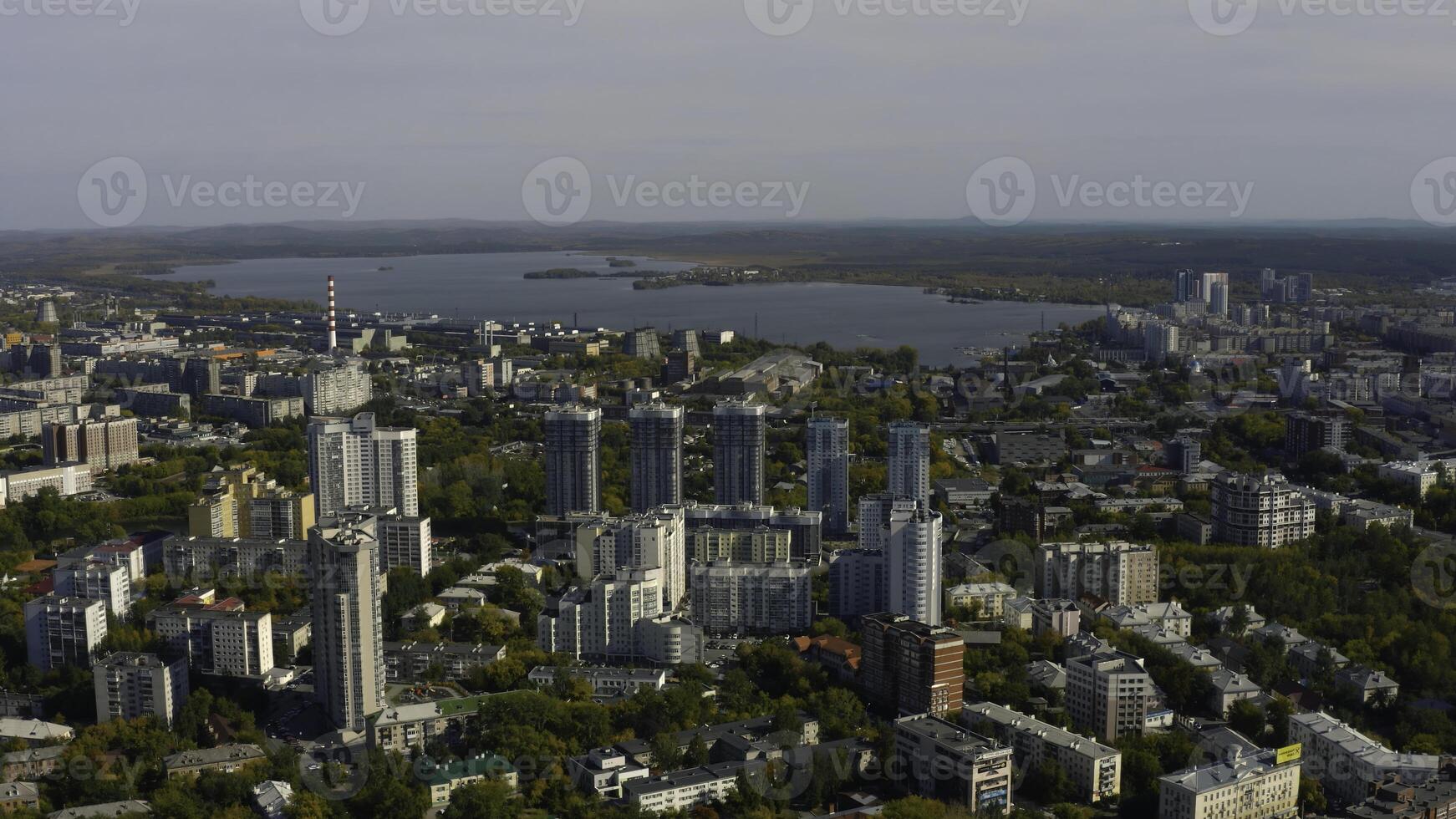 Stadt mit Hochhaus Gebäude auf Hintergrund von See und Grün Wald. Lager Filmaufnahme. modern Gebäude im schön Grün Stadt mit See und Wald Horizont. oben Aussicht von Panorama von modern Stadt im foto