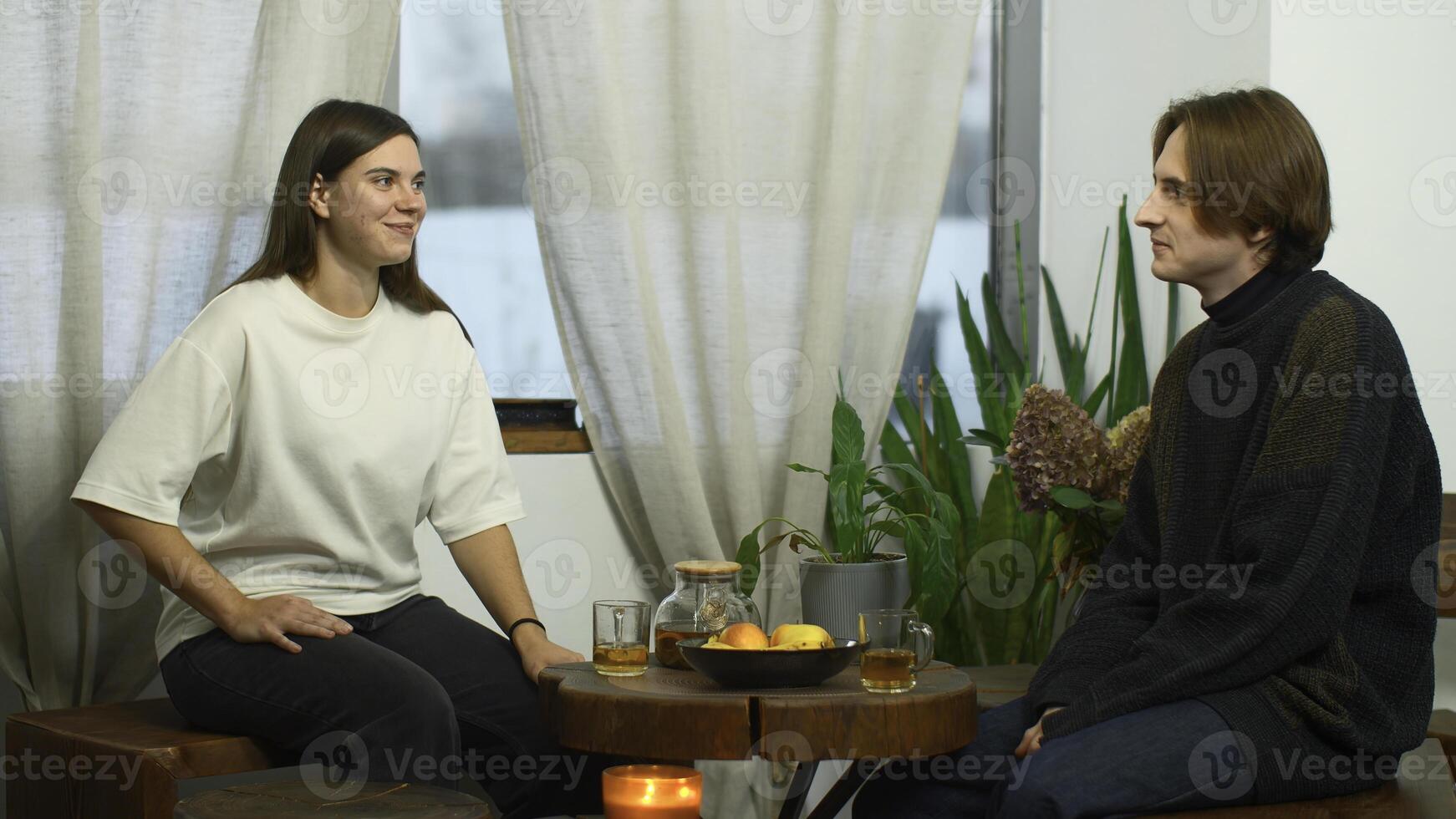 Studenten kommunizieren und trinken Tee im Cafe. Medien. jung Mann und Frau sind Trinken Tee und reden im Cafe. heiter Konversation zwischen jung Paar von Studenten im gemütlich Cafe foto