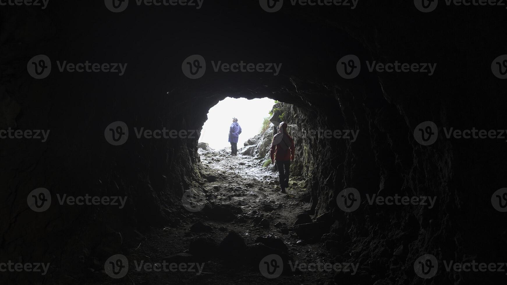 Aussicht von Höhle zu Touristen. Clip. Rückseite Aussicht von Mann Kommen aus von Höhle. Tourist kommt aus von Höhle in Licht foto