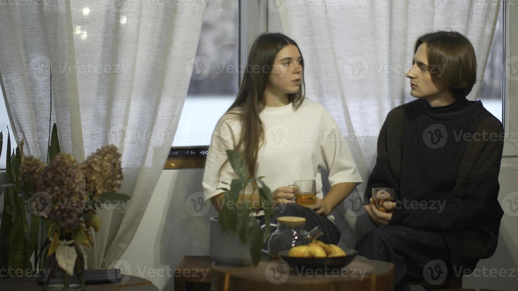 jung Mann und Frau sind reden Über Tee im Cafe. Medien. jung Paar von Studenten sind reden mit Tee im gemütlich Cafe. Paar auf Schüler brechen mit Tee und komfortabel Konversation foto