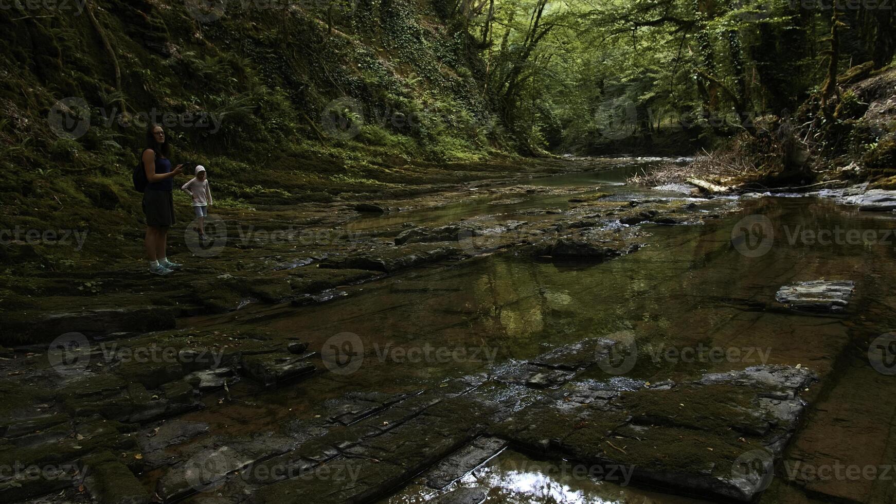 jung kaukasisch Mädchen Stehen vorsichtig auf steinig Pfad und Fluss und nehmen Bilder auf Kamera. kreativ. Konzept von aktiv Lebensstil und wandern. foto