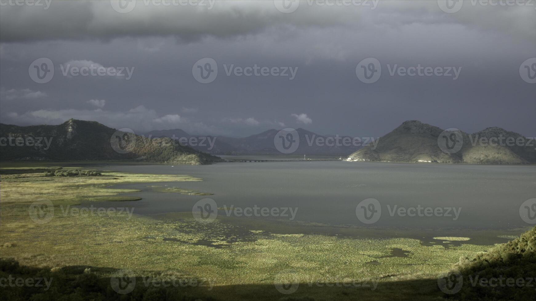 Sonne und Schatten auf Grün Wiese und ein See. kreativ. Ruhe Wasser und Berge auf wolkig Himmel Hintergrund. foto