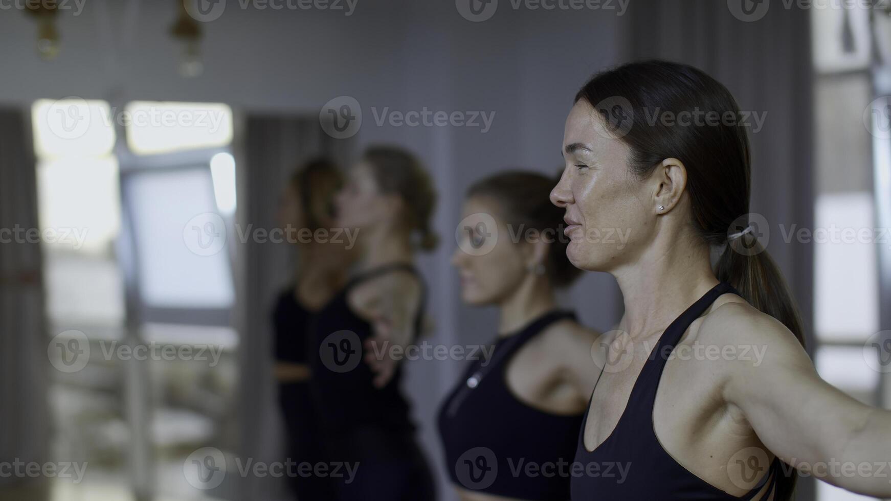 Gruppe von sportlich Menschen während ein Fitnessstudio Ausbildung mit ein Coach. Medien. Mädchen Gruppe von Sportler schwingen Hände Vor beginnend ein trainieren Yoga Sitzung. foto