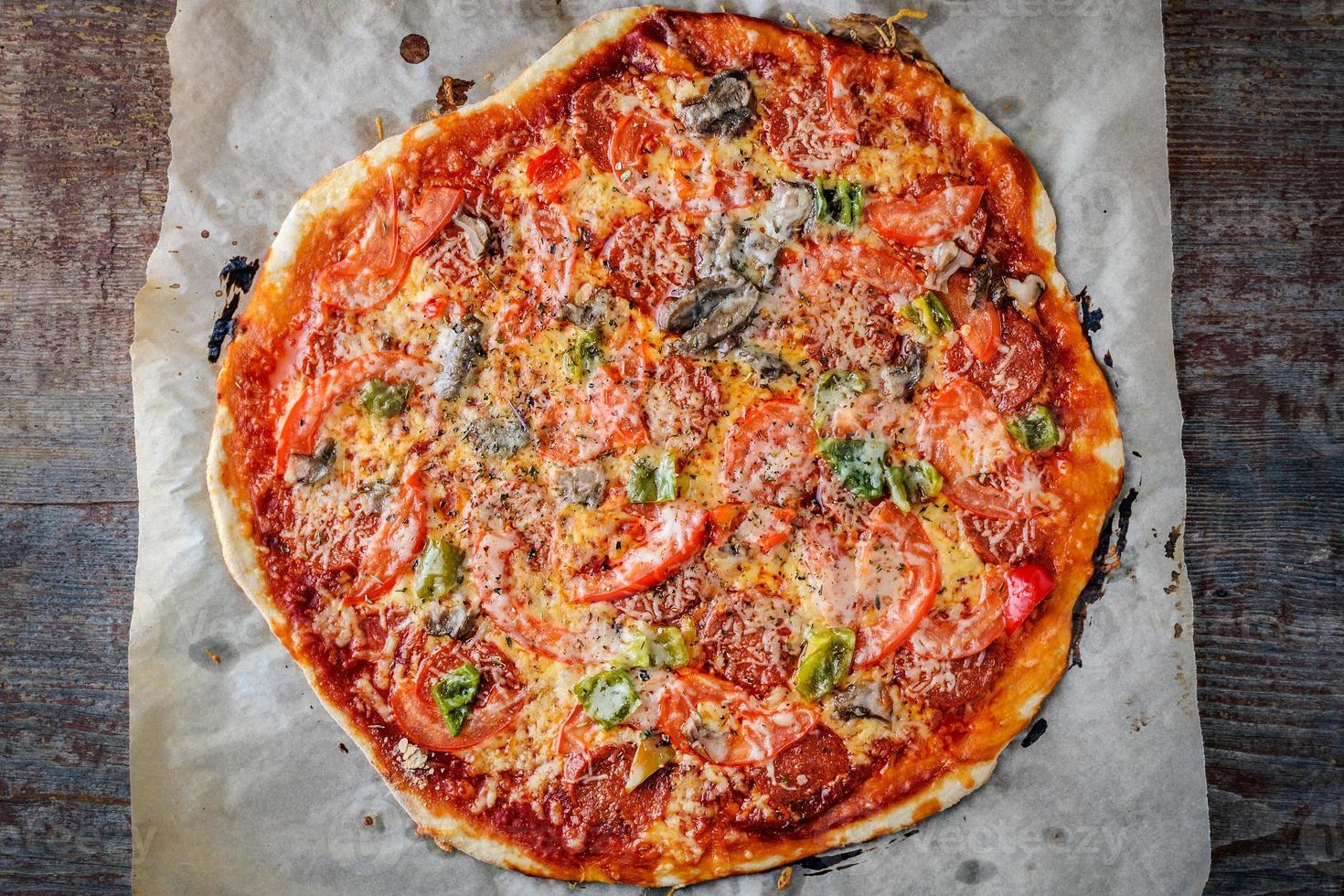hausgemachte italienische Pizza mit Salami und Parmesan auf Holzhintergrund. foto